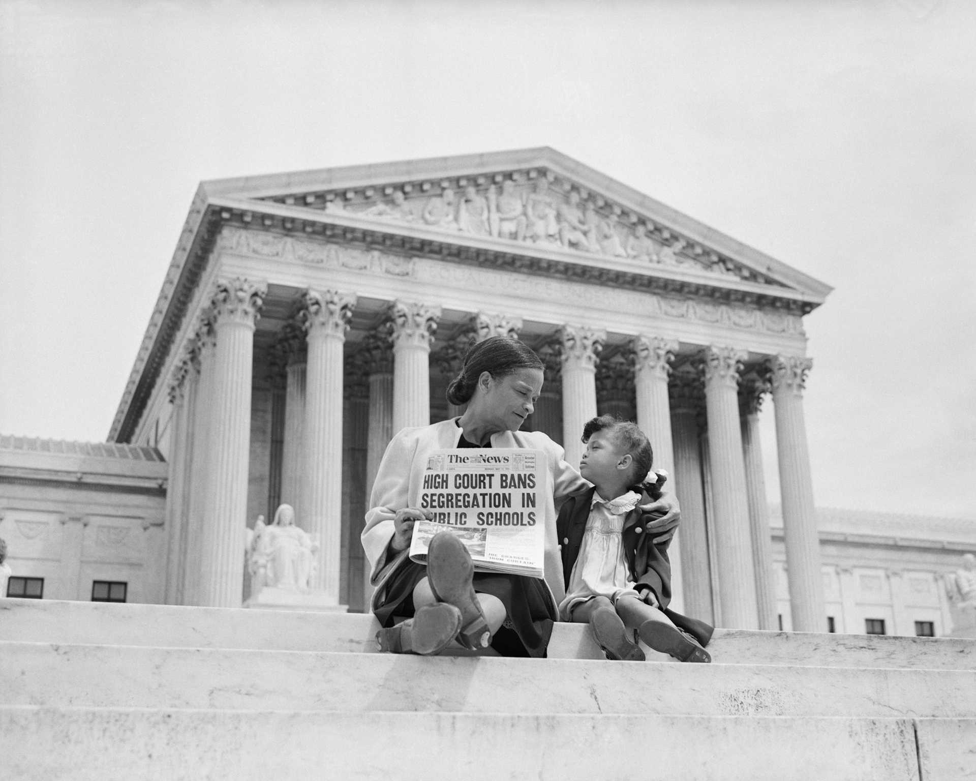 Mrs. Nettie Hunt, sitting on steps of Supreme Court, holding newspaper, explaining to her daughter Nikie the meaning of the Supreme Court's decision banning school segregation