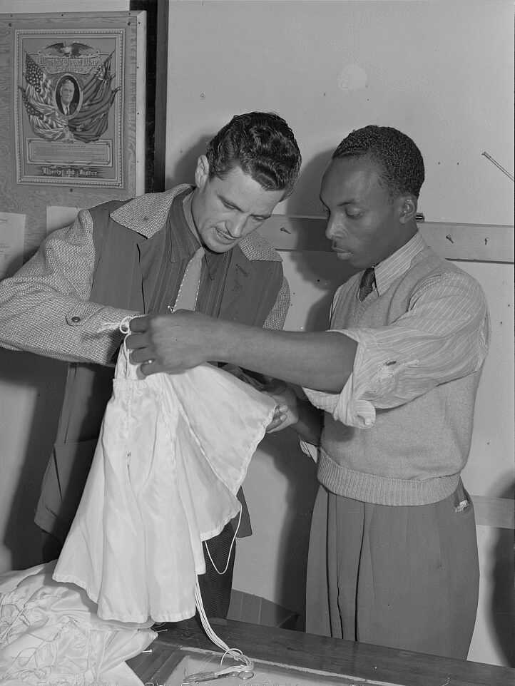Photograph of Howard “Skippy” Smith, president of Pacific Parachute Company, examining a pilot parachute with the chief inspector of Standard Parachute