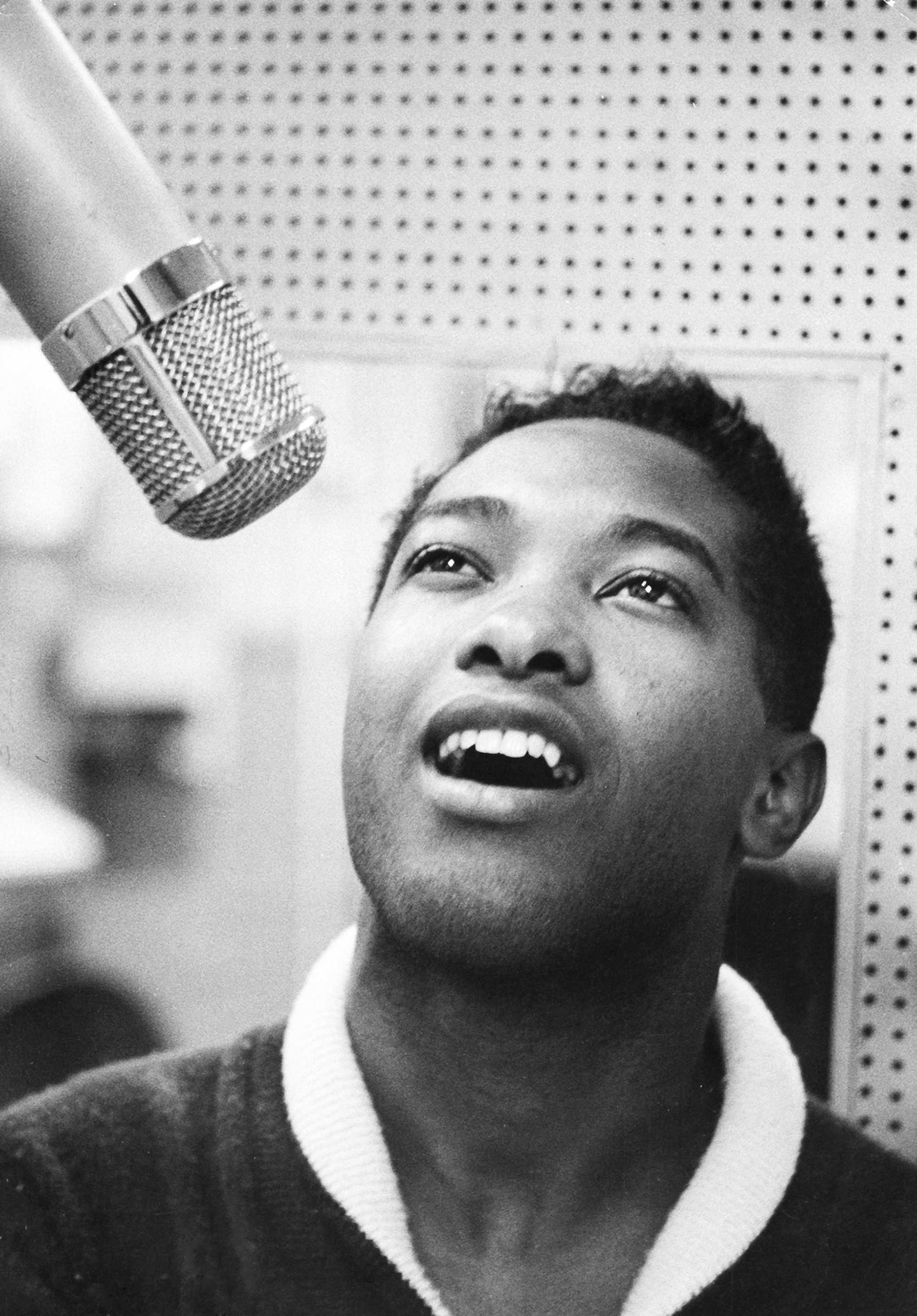 Close up black and white photograph of Sam Cooke singing into a microphone