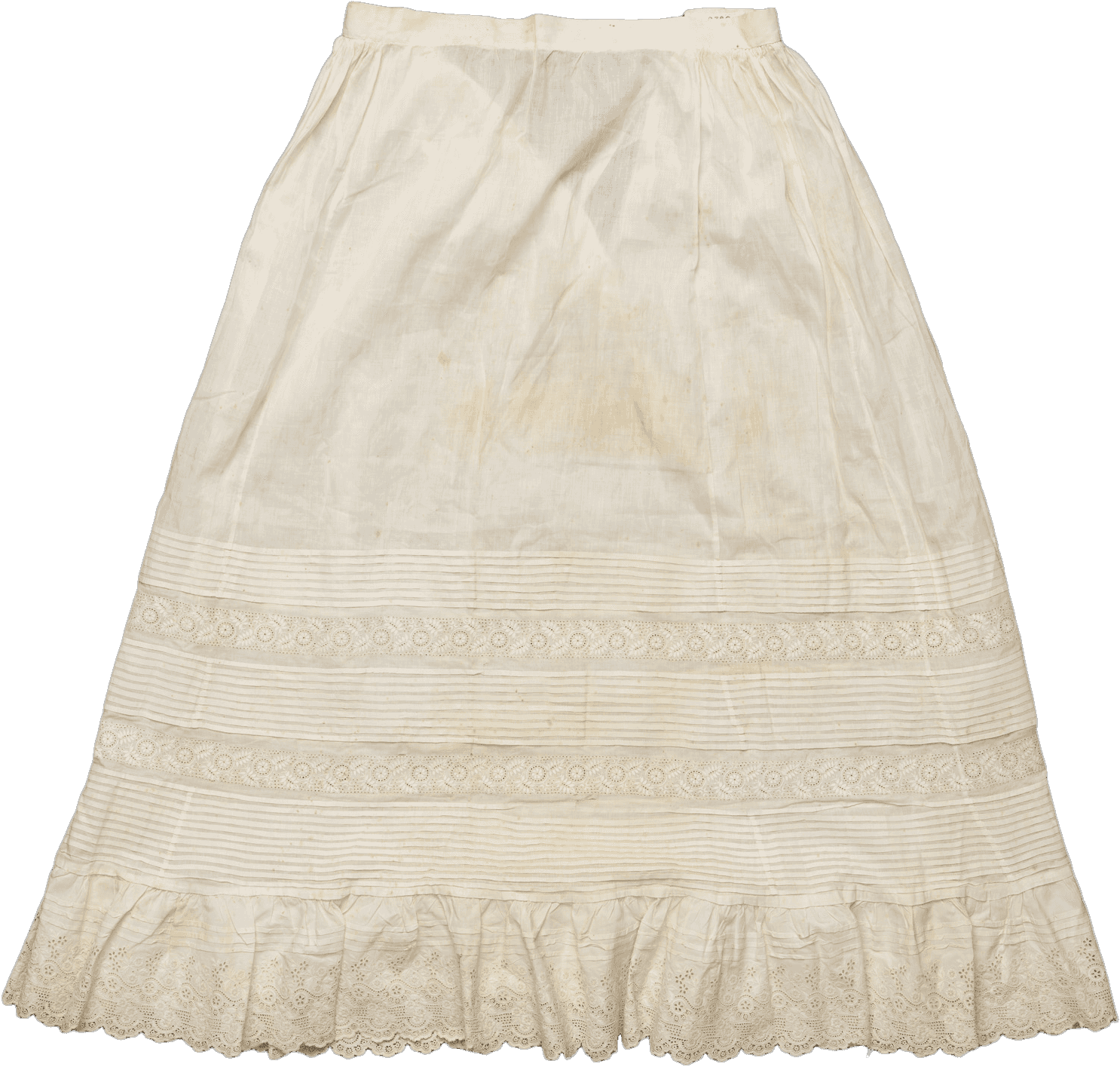 A handsewn tucked petticoat with embroidered detailing. The white petticoat has a tie closure at the waist. The lower half of the petticoat has multiple tiers of tucked detailing alternating with rows of embroidered flora. Along the hem is more elaborate embroidery with a scalloped edge. The fabric is discolored with small areas of loss. There is a handwritten label sewn in the interior waistband.