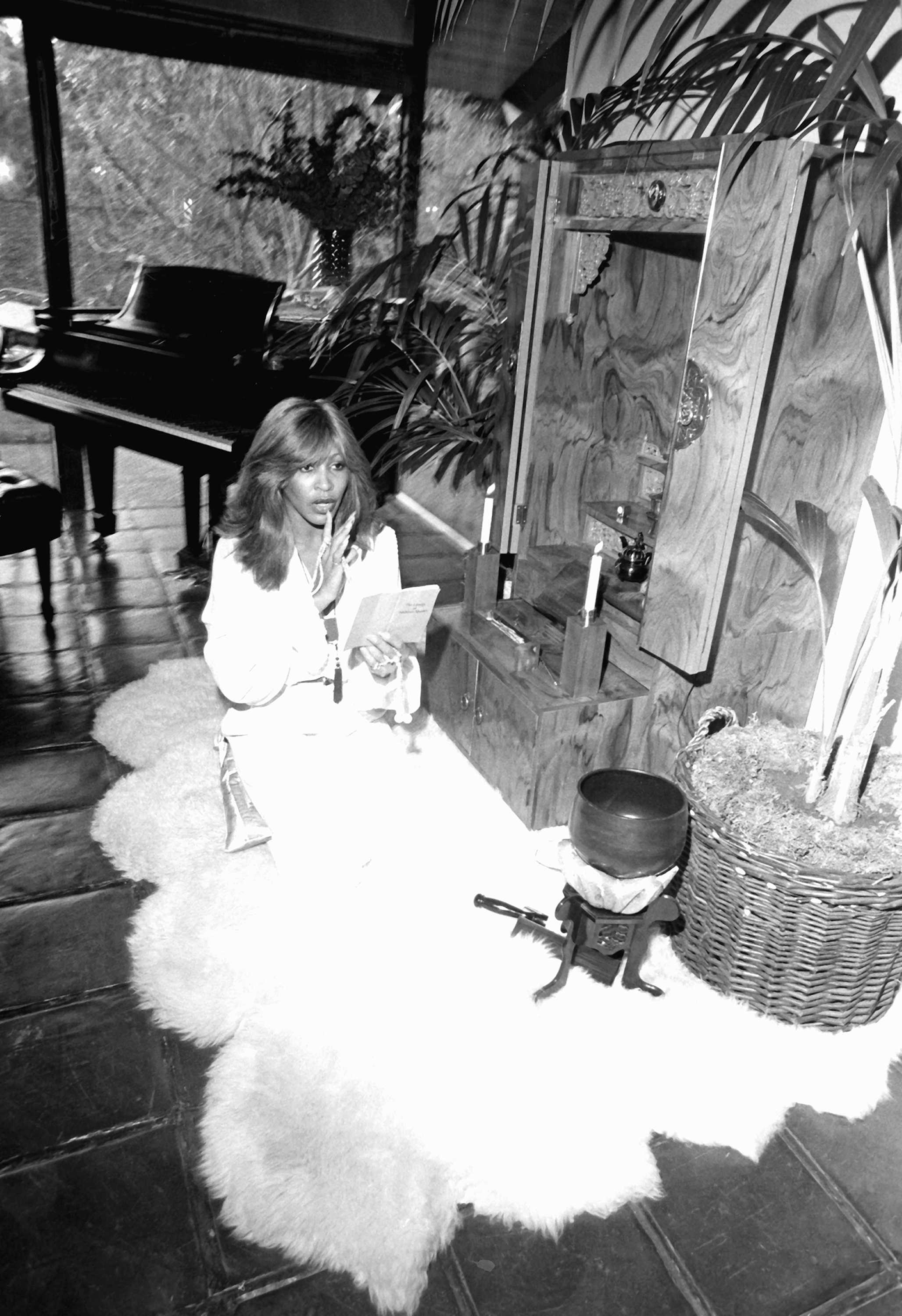 Black and white photograph of Tina Turner performing a Buddhist ritual at her home altar