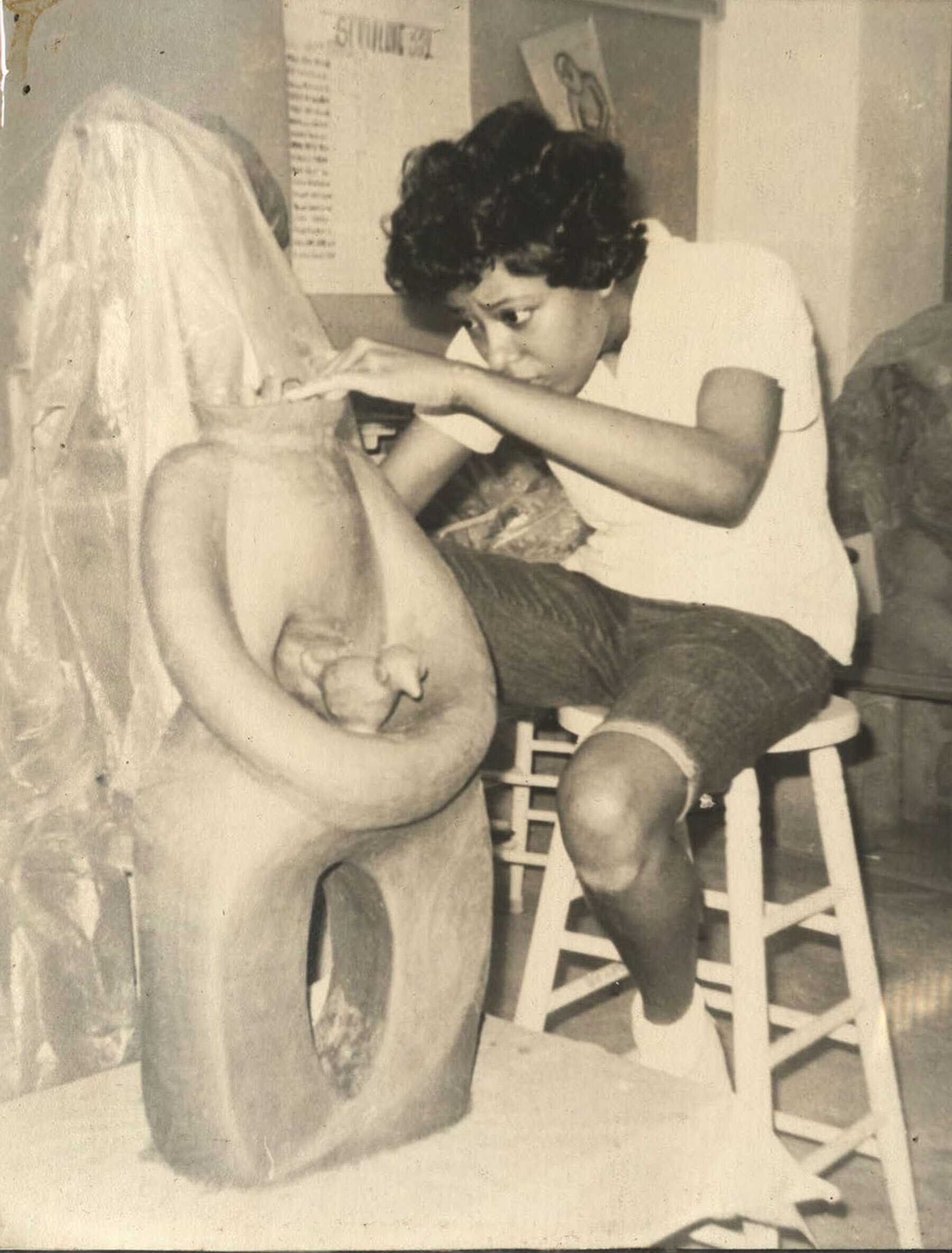 A black and white photo of an artist working on a sculpture