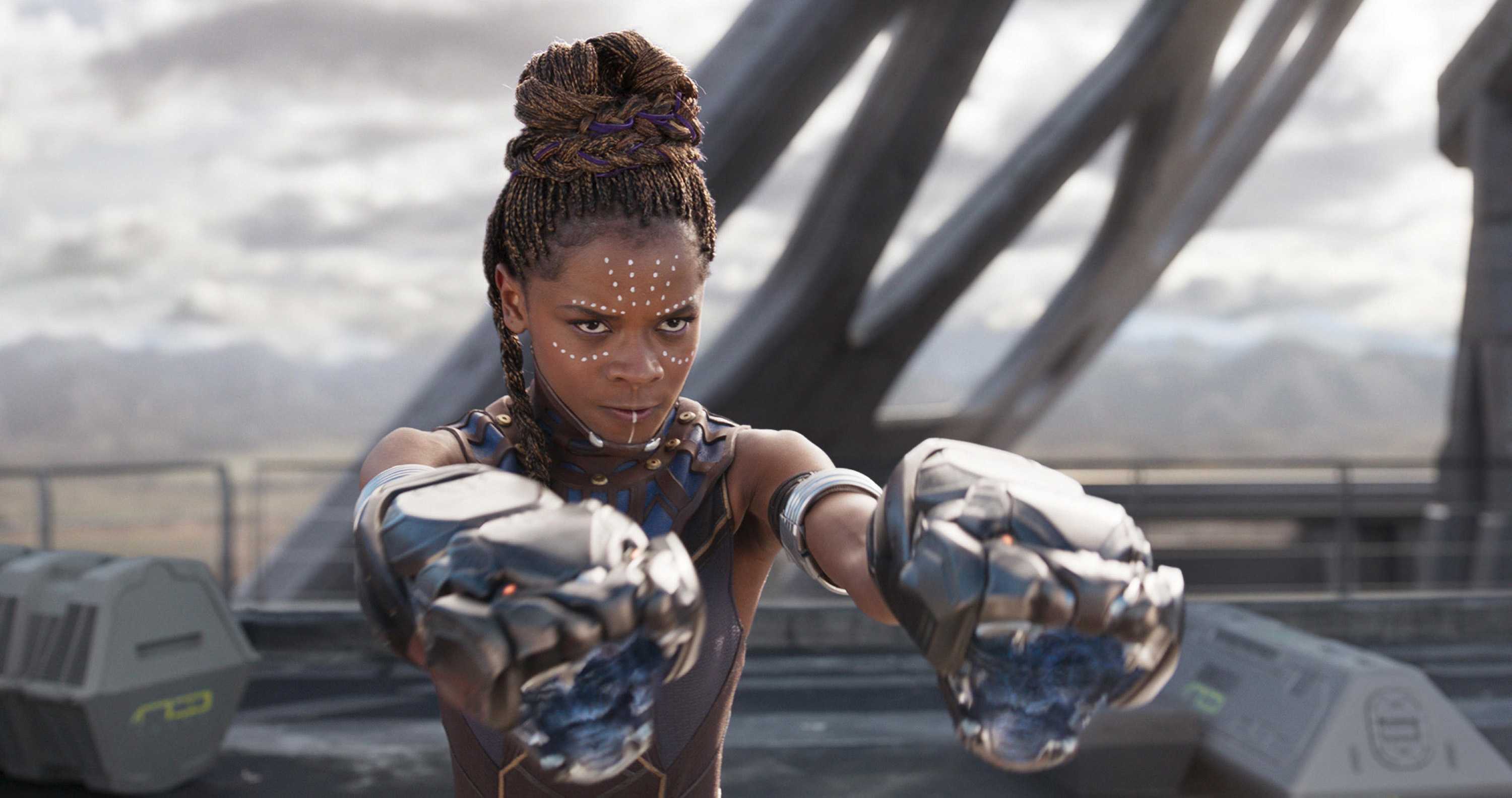 Shuri is fighting with her Vibranium Gauntlets. She is focused and determined and holding her arms out straight.