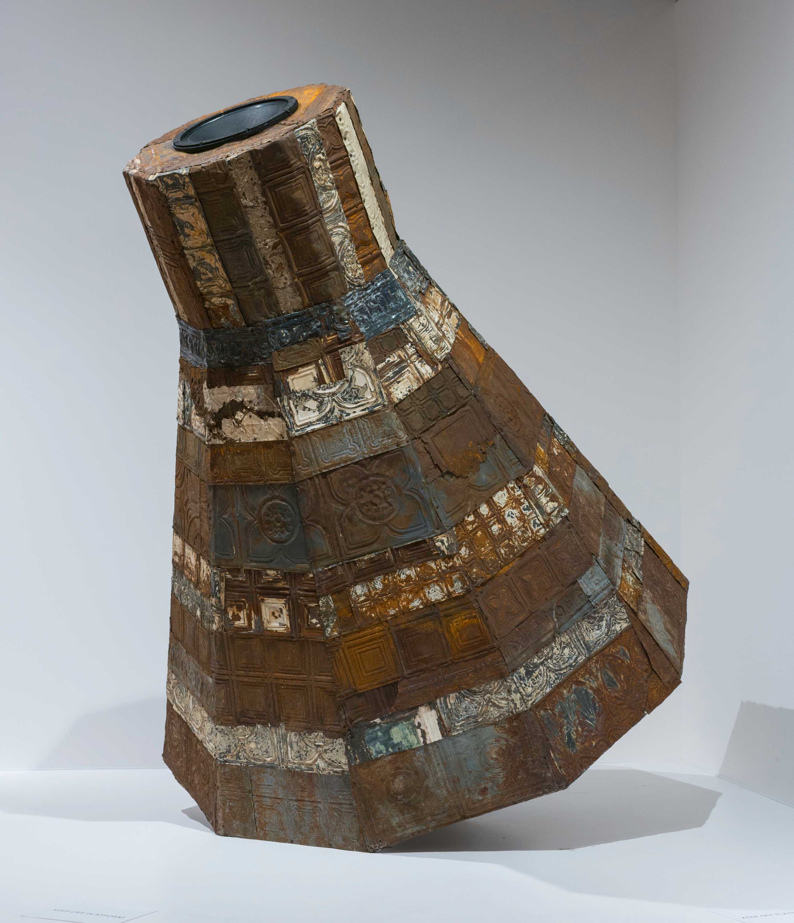 Mixed media art with tin plates and wood planks in the shape of a NASA Mercury spacecraft.