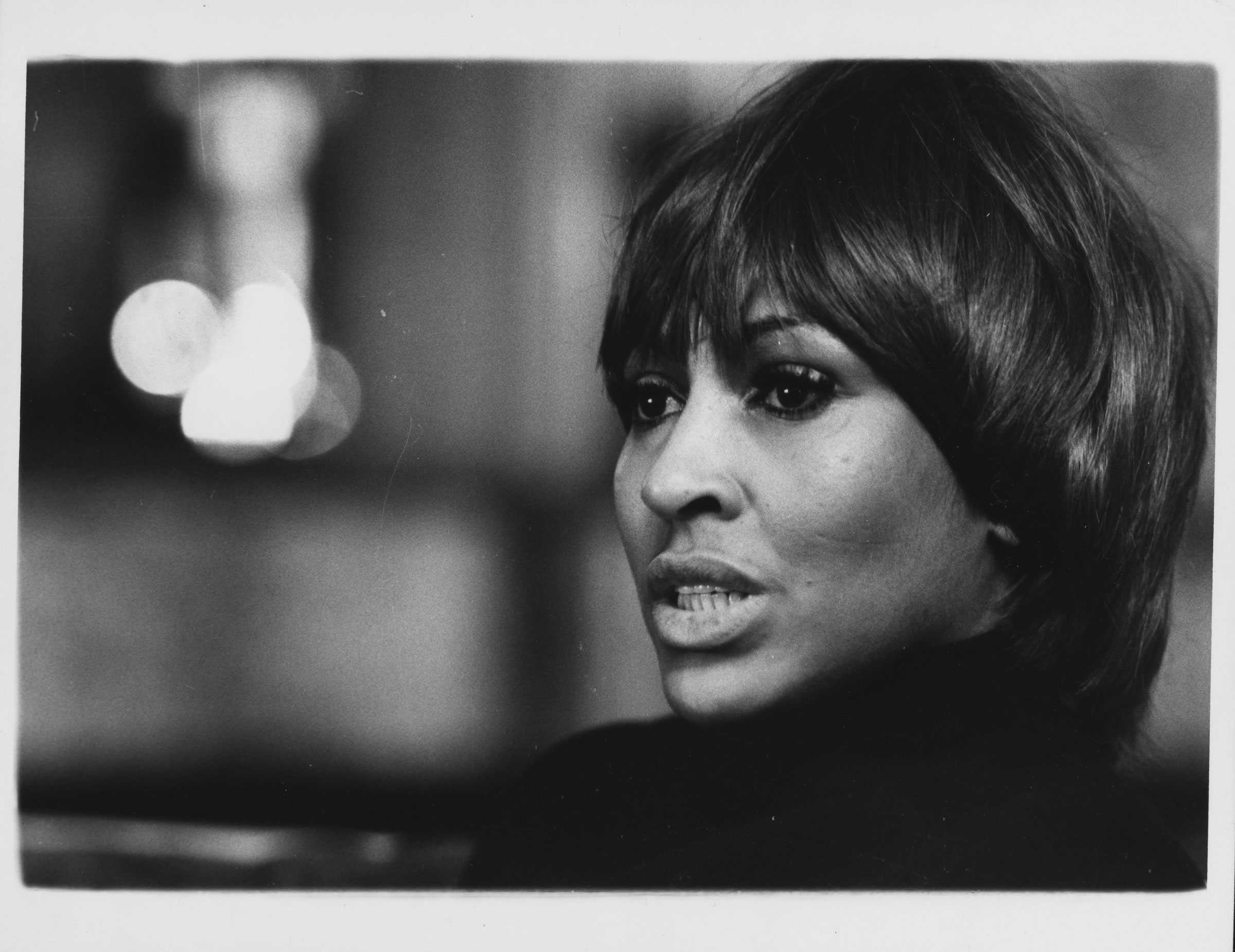 Black-and-white portrait of a woman with short hair, set against a blurred background.