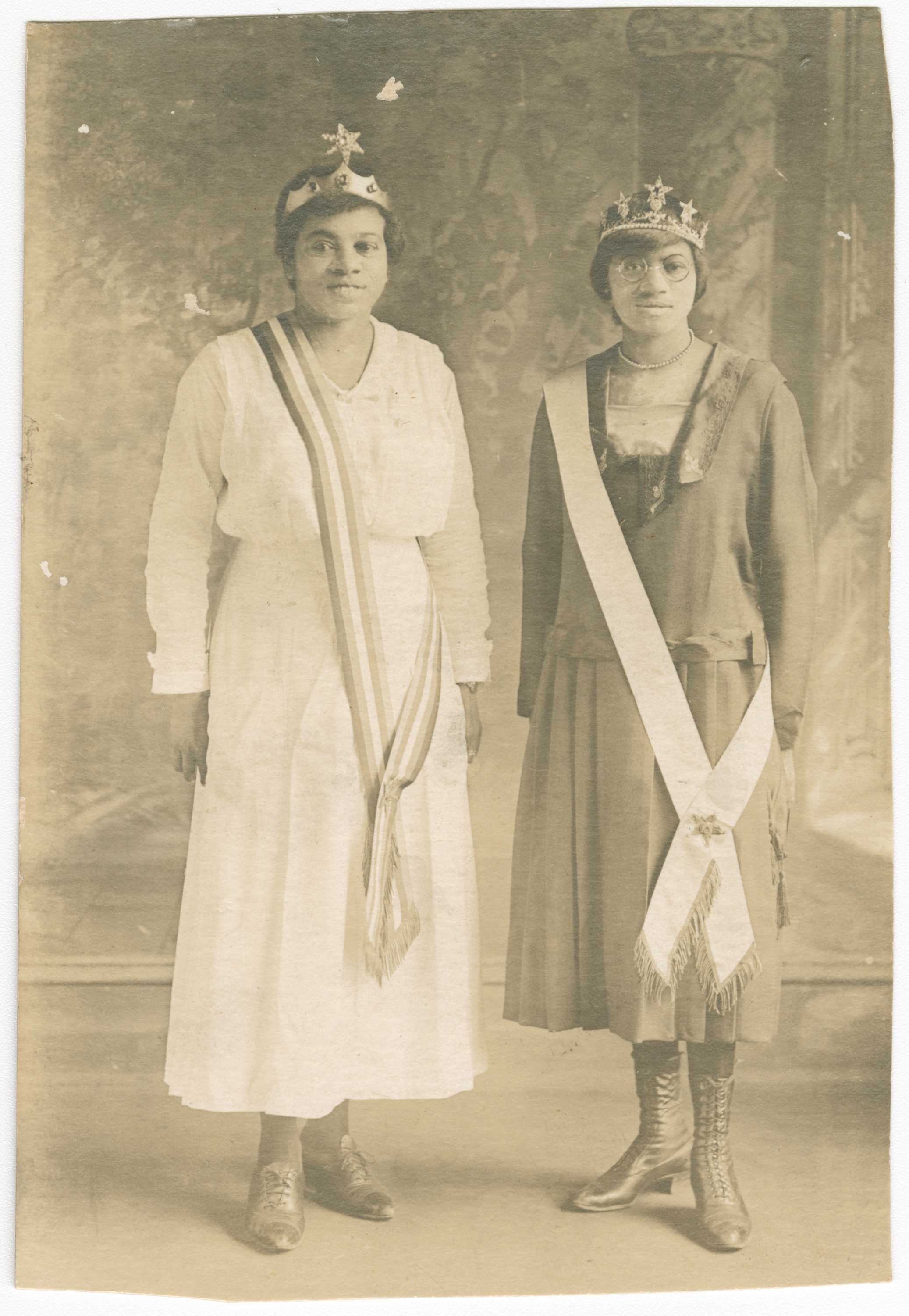 Black and white photographic postcard of Magdalene Hendricks (right) and her sister (left) wearing tiaras and sashes across their right shoulders.