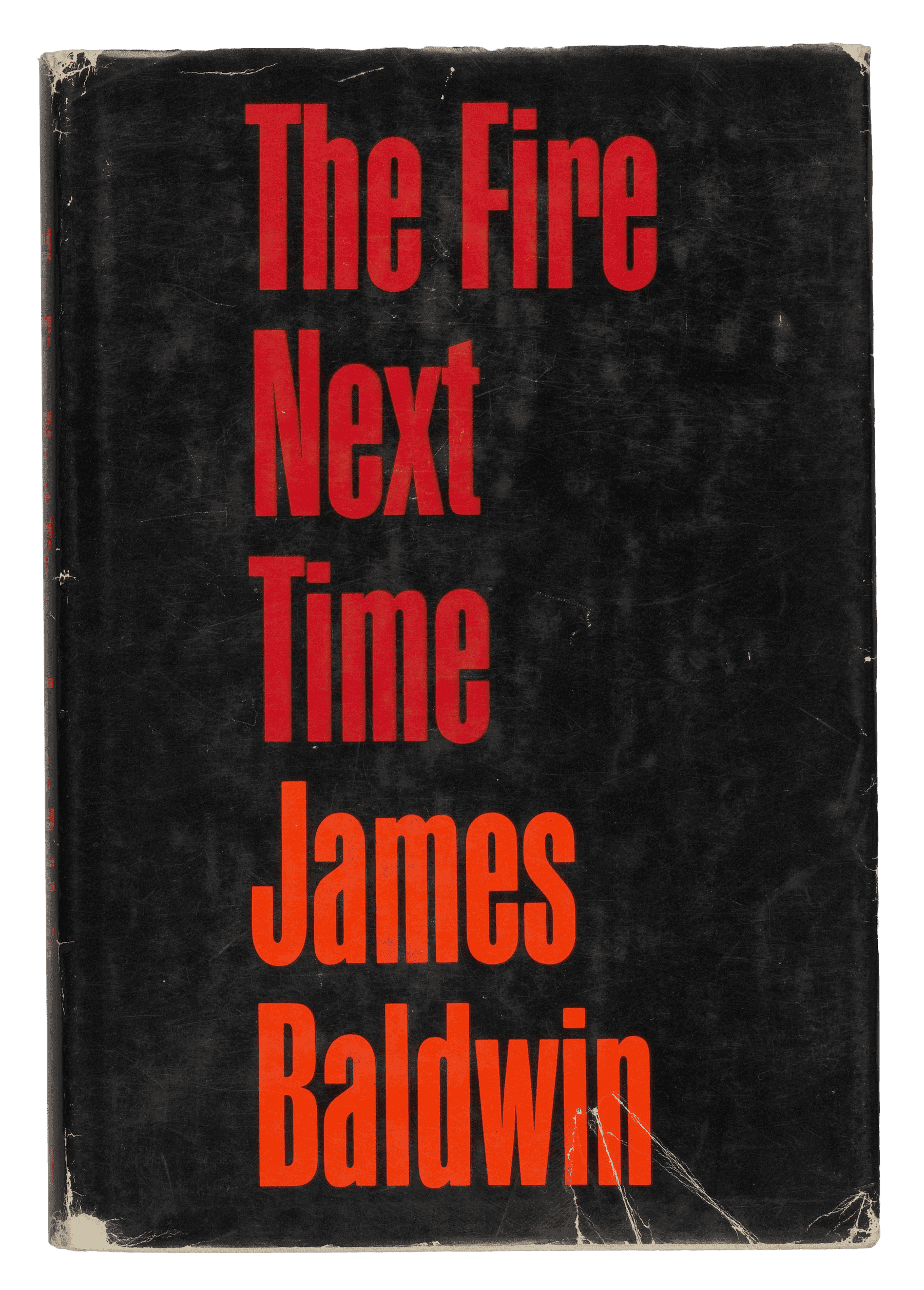 A hardback copy of The Fire Next Time by James Baldwin. The book has a paper cover with clear plastic cover over top of the book. The paper cover is black with red and orange type. The front of the paper cover reads: [The Fire / Next / Time] in red and [James / Baldwin] in orange, centered but aligned to the left. The back of the paper cover is entirely taken up by a black-and-white picture of James Baldwin. The picture is a close-up of Baldwin, who has his hands crossed in front of him and is wearing a jacket. The hardback book itself is white with red type. The interior pages, one hundred and twenty-three in total, front and back included, are off-white paper with black type, and no images. One of the interior pages has a stamp that reads: [John R. McElderry].