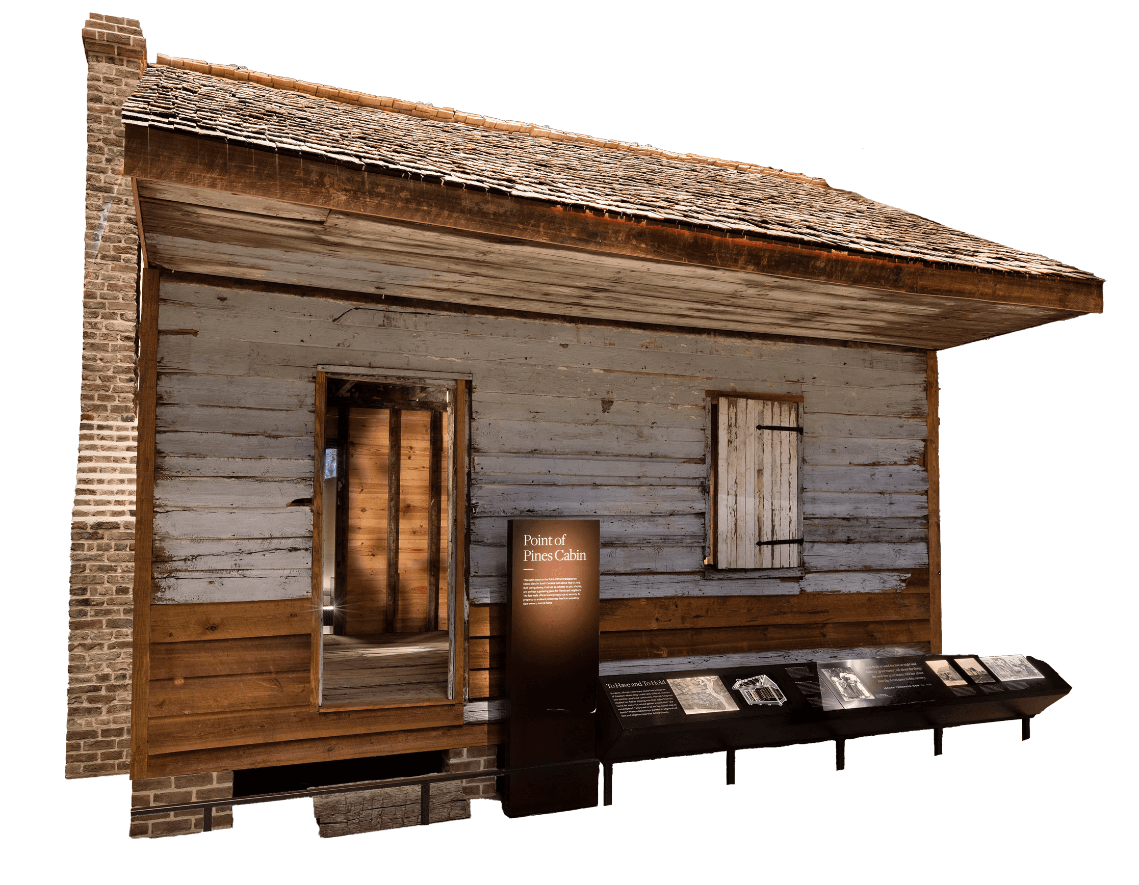 Within the museum, a full view of the Point of Pines Cabin, which has worn sides and roof.