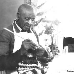Black and white photograph photograph of George Washington Carver knitting.