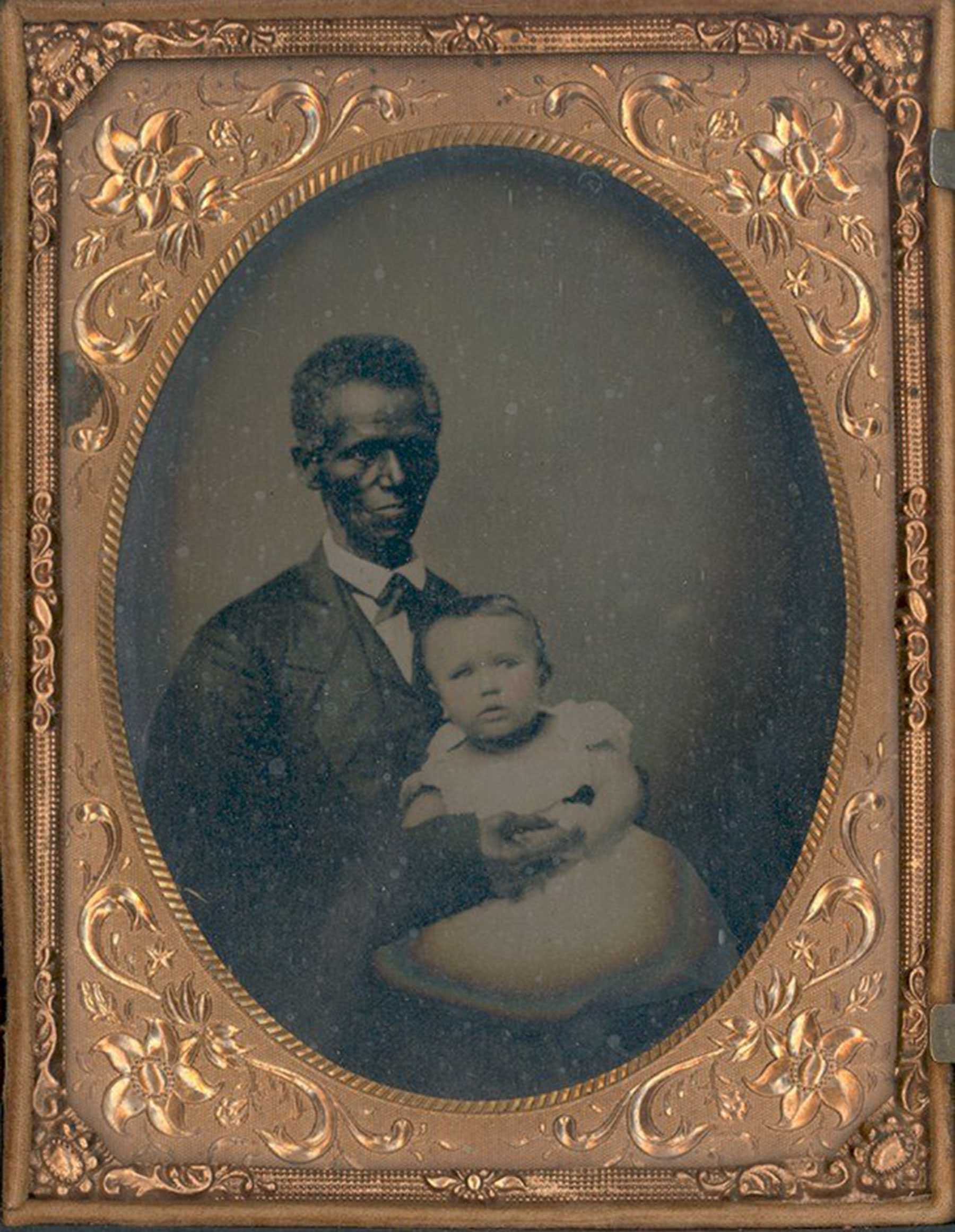 Portrait in an ornate frame showing a man holding a baby, illustrating historical family photography.