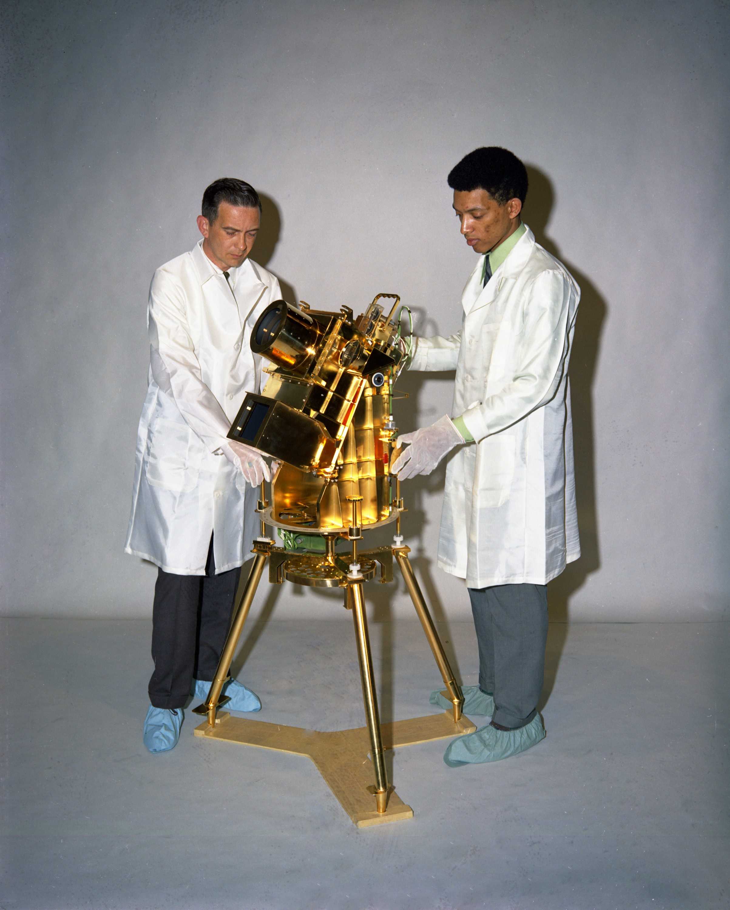 Dr. George Carruthers and another scientist examining a gold-plated ultraviolet camera/spectrograph.