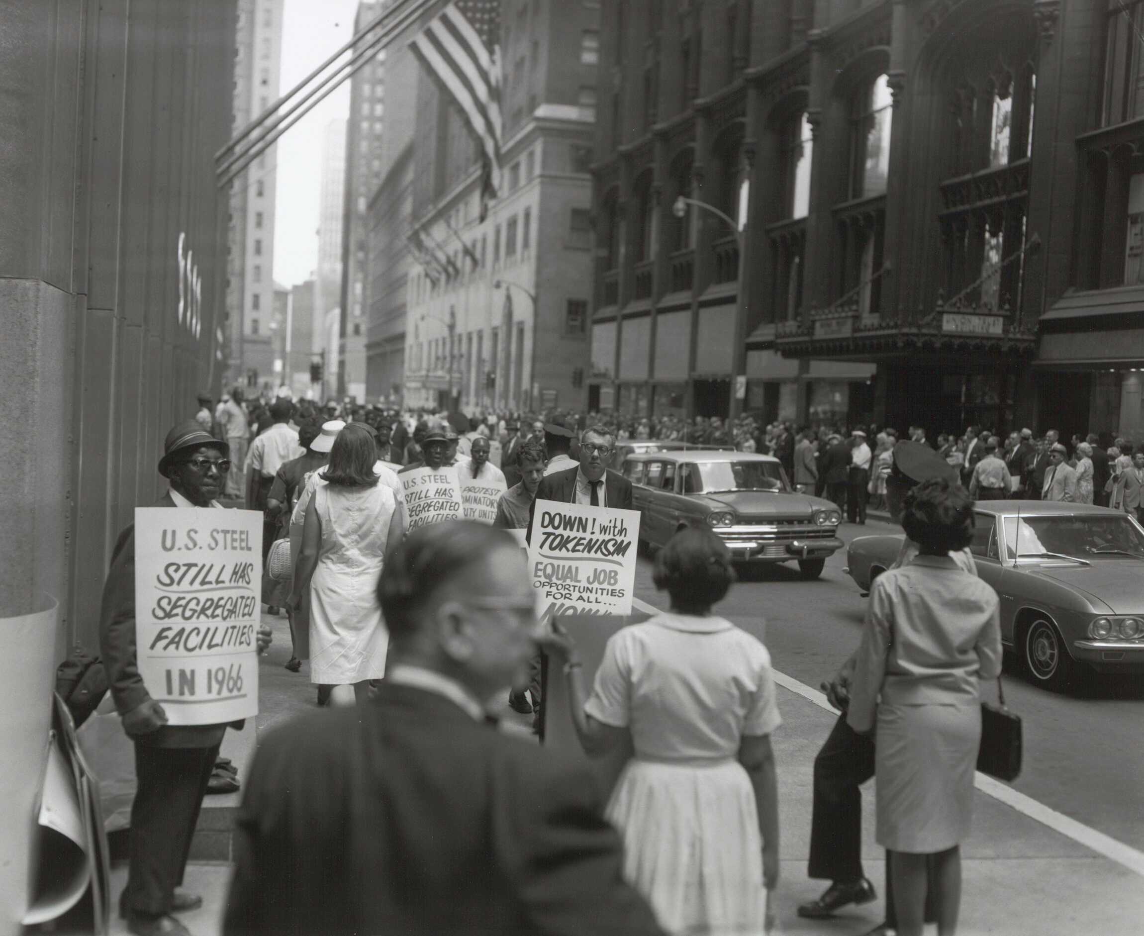 A black and white photograph of NAACP activists protesting segregated work spaces at U.S. Steel.