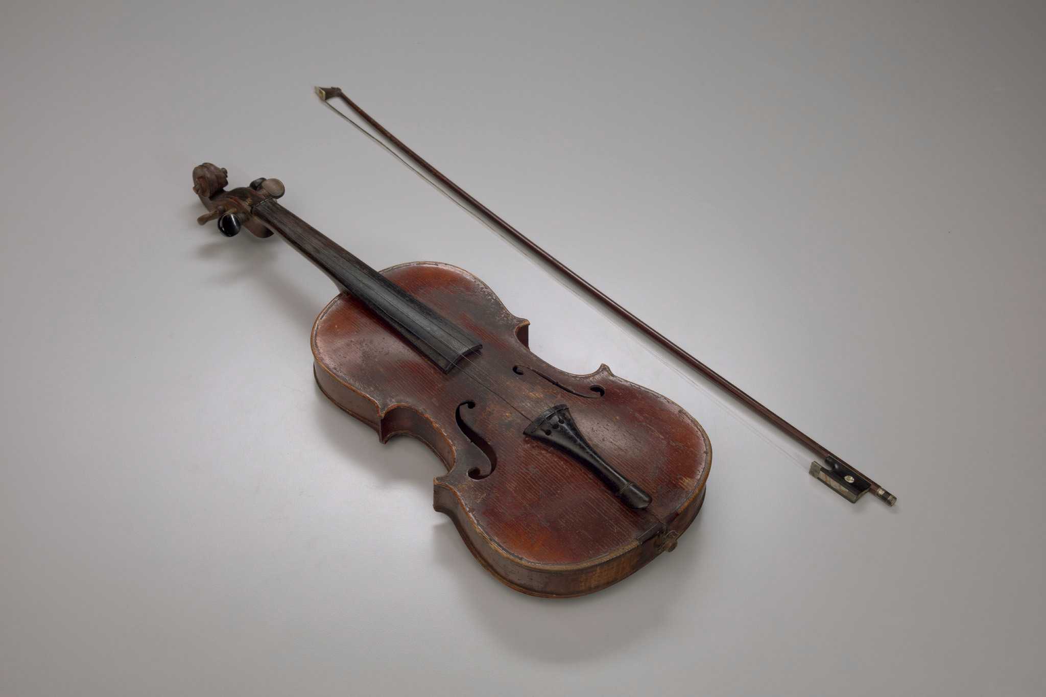 A violin (.1a) with a bow (.1b) stored in a wooden case (.2), all owned and played by Jesse Burke, who used the violin during and after enslavement.

The violin (.1a) has a reddish-brown stained wooden body, neck, peg box, and scroll. The pegs, fingerboard, and tailpiece are made of wood painted black. A small piece of mother of pearl is attached at the center top of each peg. The strings are made from steel. A paper label is adhered to the interior back of the violin body, which can be seen through the sound holes. Printed on the label in black text are the words: "Antonius Stradiuarius Cremonensis / Faciebat Anno 1726".

The bow (.1b) has a rod made from a dark-stained wood with a metal tension screw. The frog is made from wood painted black and inlaid with mother of pearl and a metal ferrule. The tip is edged with a panel of an ivory imitation material. The bow hair is made from horsehair, though the horsehair is broken with several strands still attached and extending from the tip in varying lengths.

The wooden case (.2) is painted black and has a hinged lid that opens with two (2) metal hinges. On the opening side are two (2) metal tension clasps with one (1) locking hinge at the center. There is a metal plate with a keyhole to the right of the center hinged lock. A metal handle is attached at either side of the keyhole plate. The interior of the bottom and the lid is lined with a red wool and cotton blend flannel. There are two flannel-covered wooden pieces at the wide side of the case that correspond to the center bouts on the body of the instrument and secure it in place inside the case. A loop of the flannel is sewn near the thin side of the lid, presumably to hold the bow.