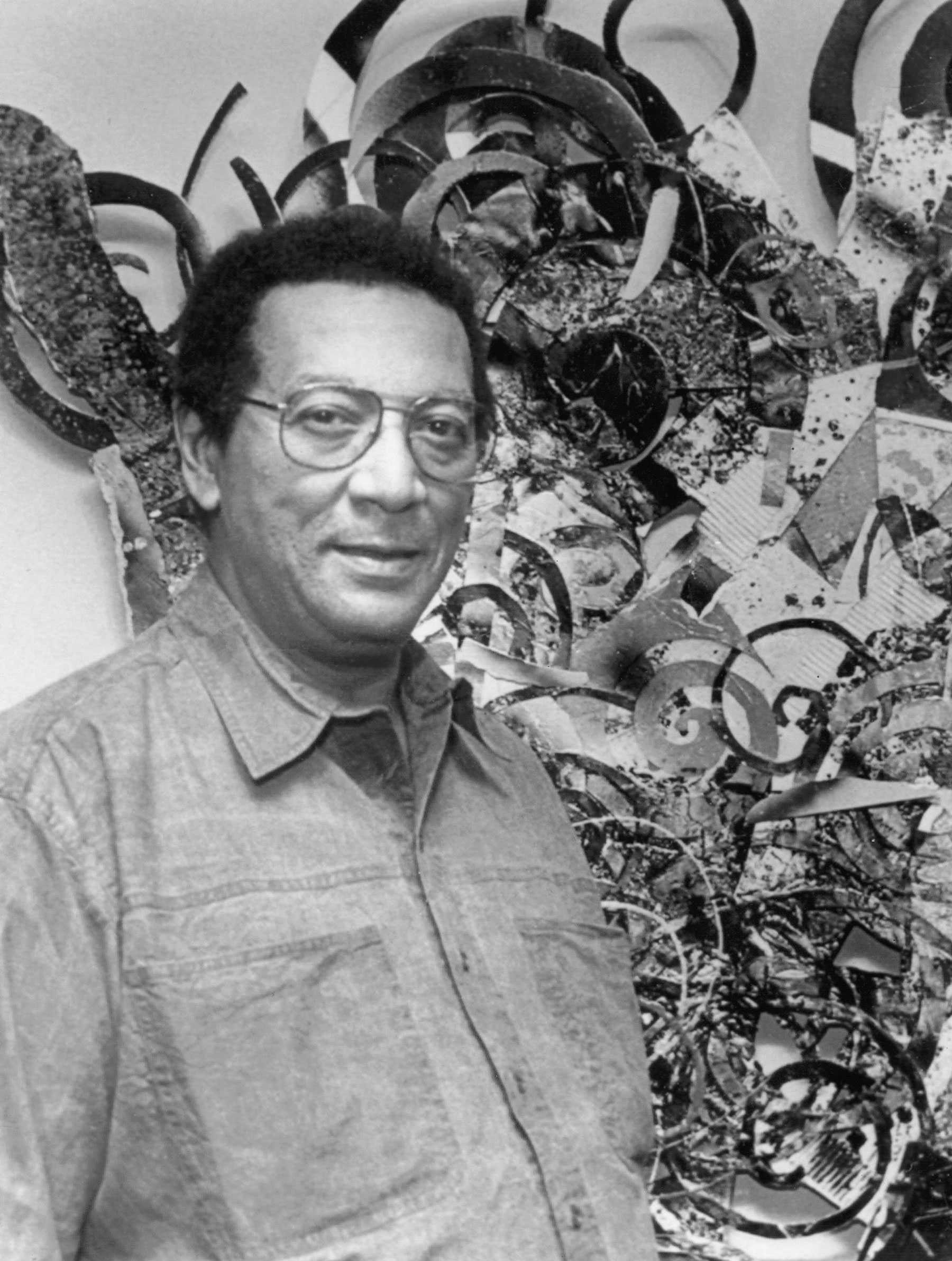 Black-and-white photo of a person standing in front of a large abstract artwork.