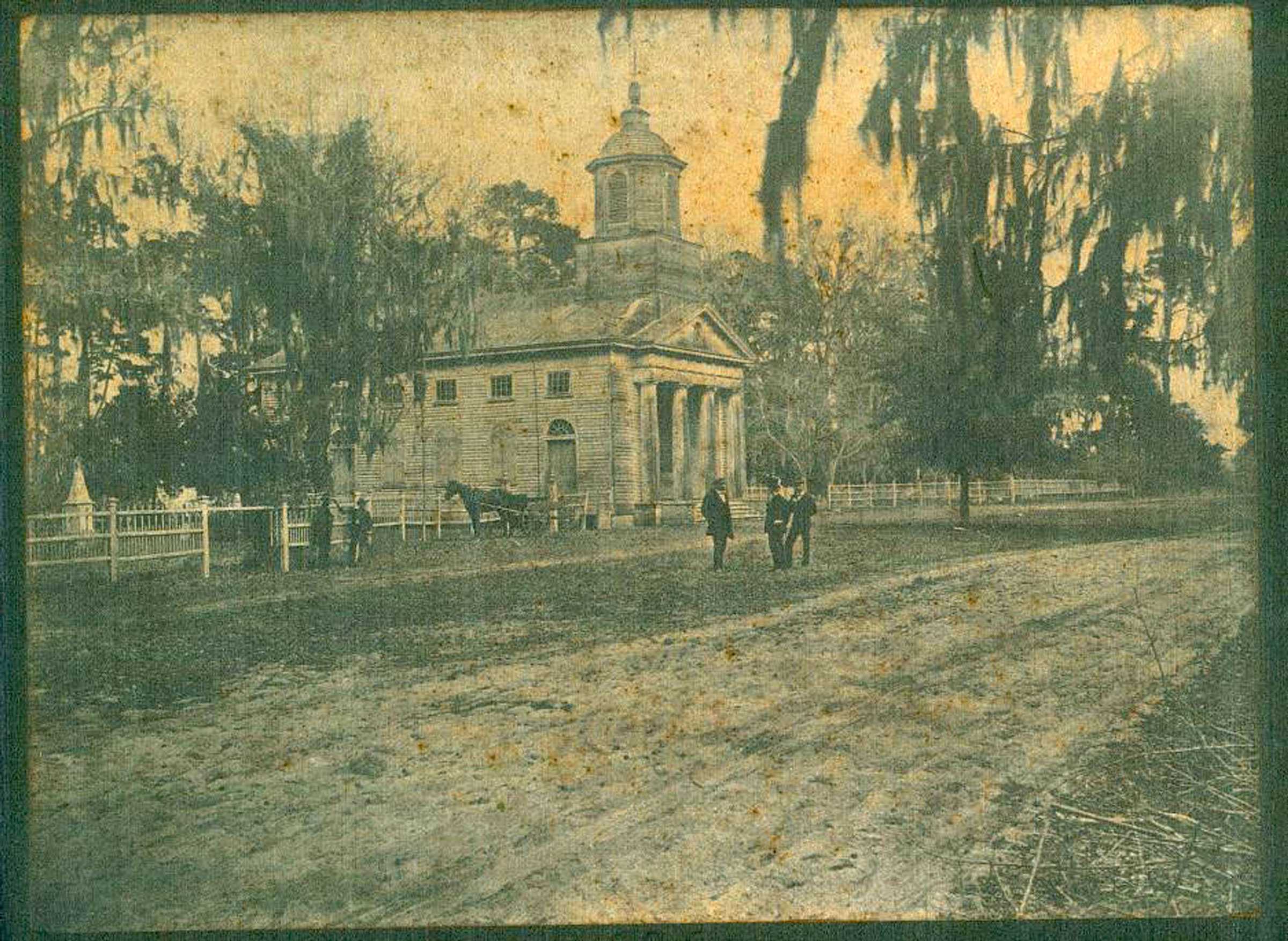 A yellowed black and white photo of the Presbyterian church and a dirt road.