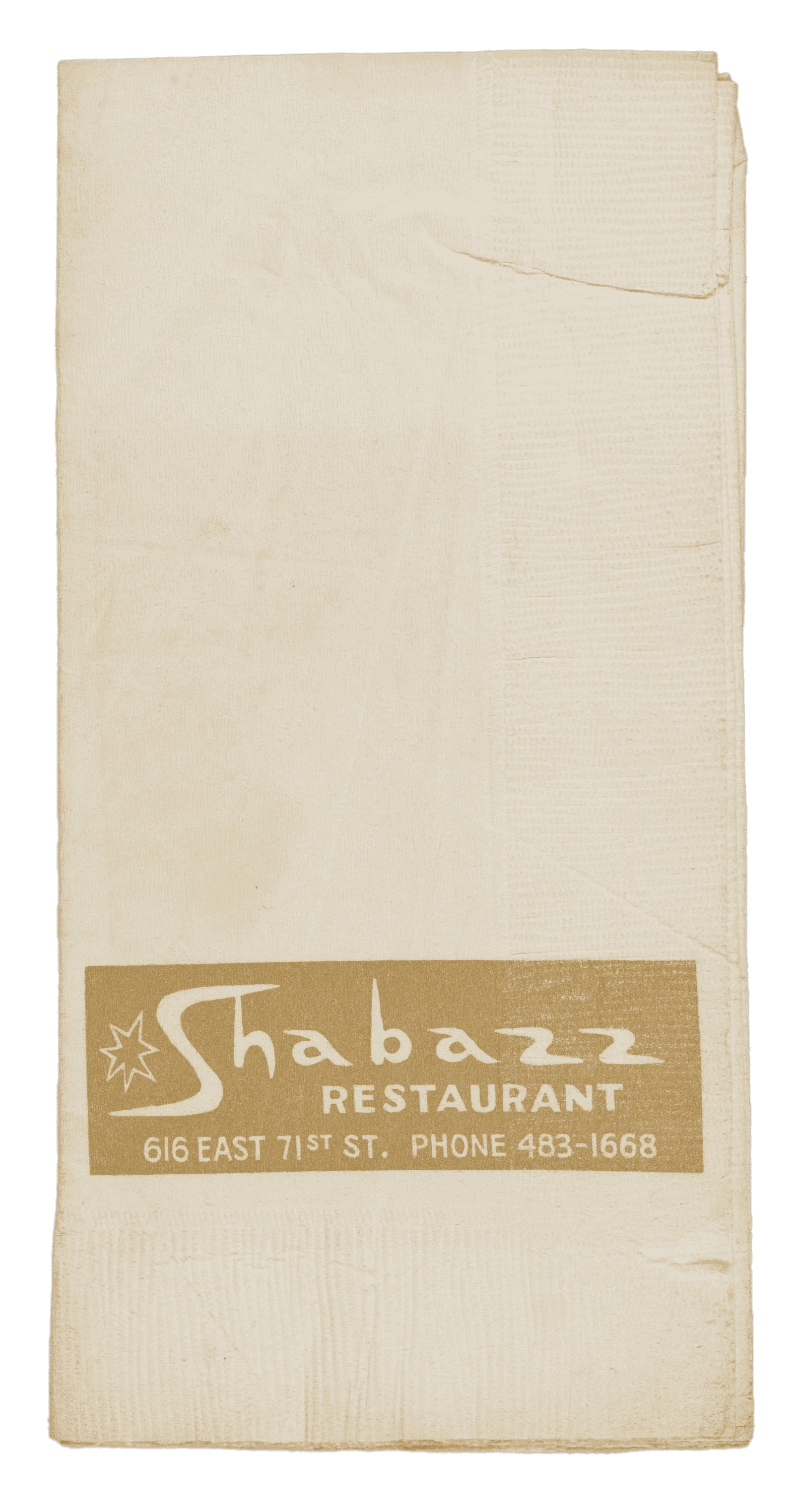 This rectangular Shabazz Restaurant paper napkin is off white with a light brown horizontal rectangular field on the lower third portion of the front