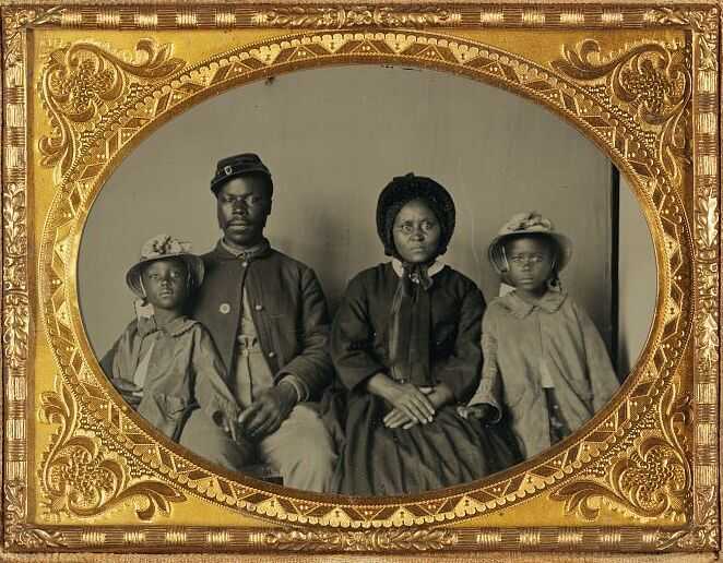 A black and white family family portrait in a gold and dark grey frame.
