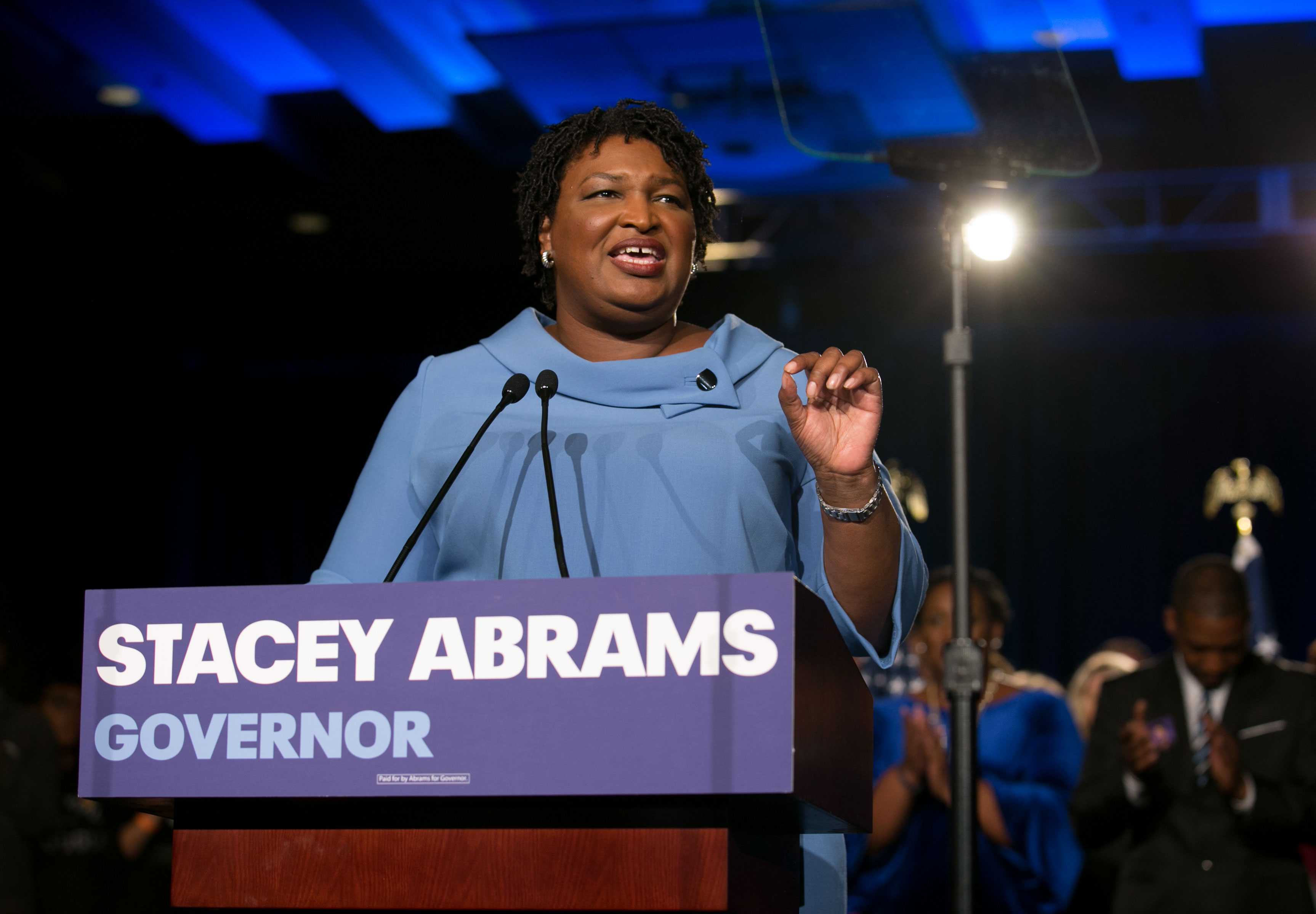 Stacey Abrams speaking behind a podium on election night. She is dressed in all blue.