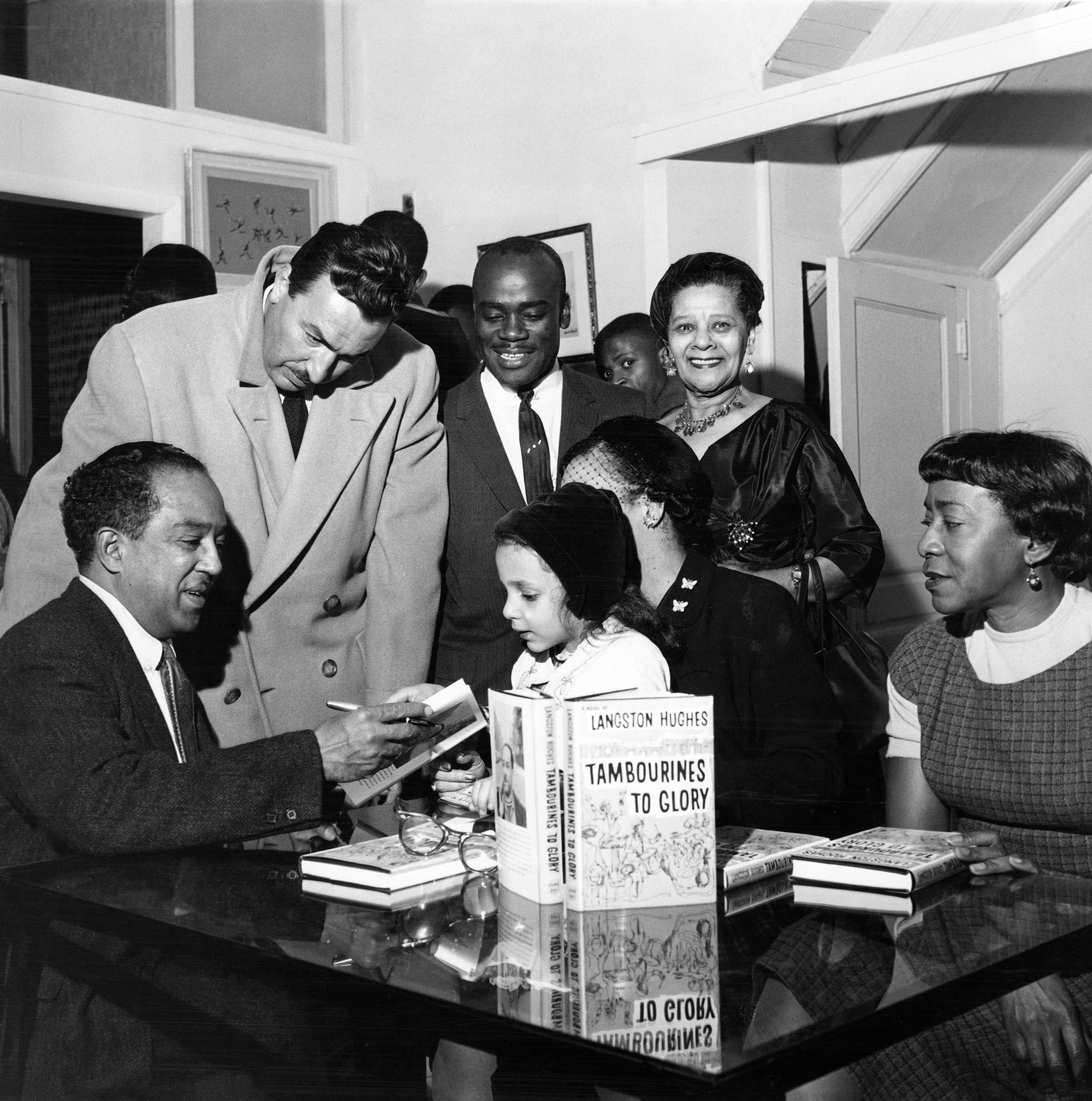 Black and white photograph of Langston Hughes autographing Tambourines for a crowd