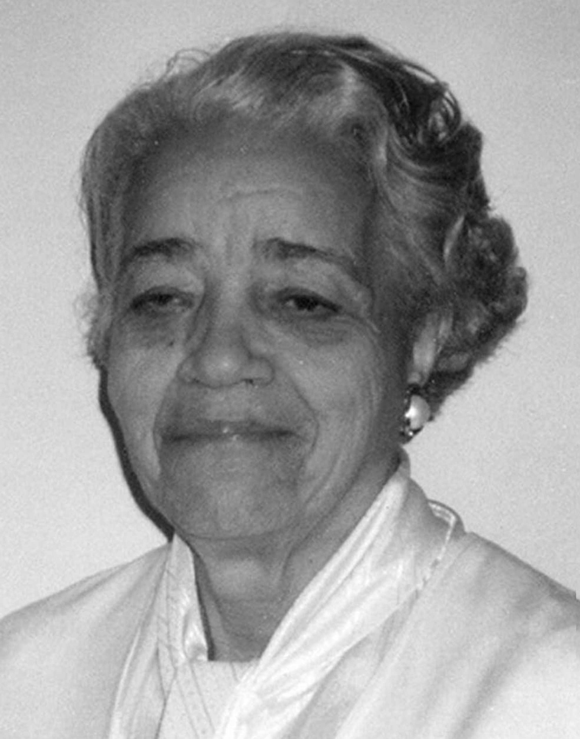 A close up black and white photo of Dorothy Vaughan. She is wearing a white silk shirt and large pearl earrings.