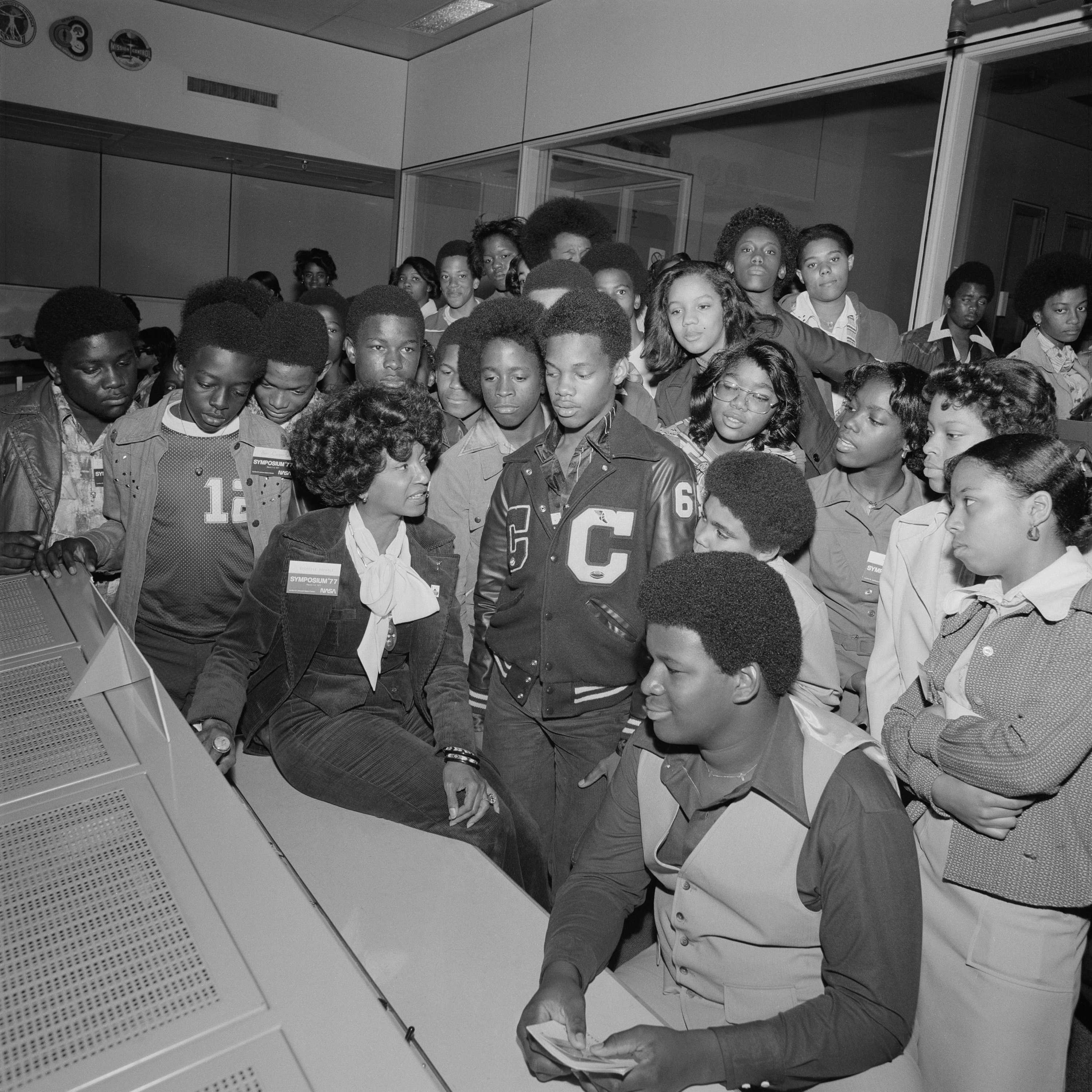 Nichelle Nichols talking while students stand around her in a school auditorium.