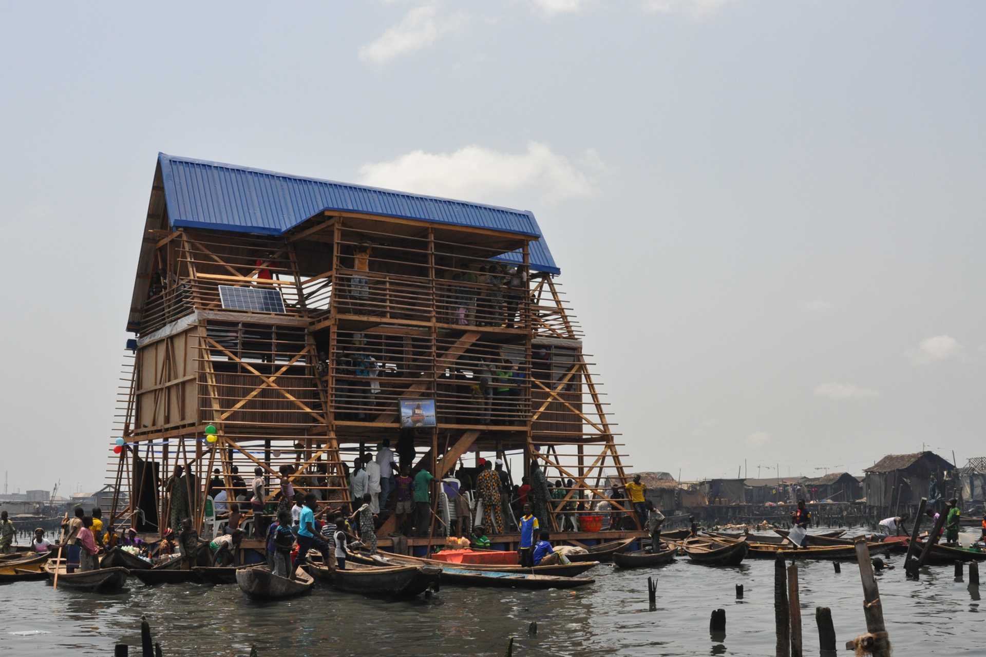The Makoko Floating School is an open aired wooden building that sits on water. Many boats surround the school.