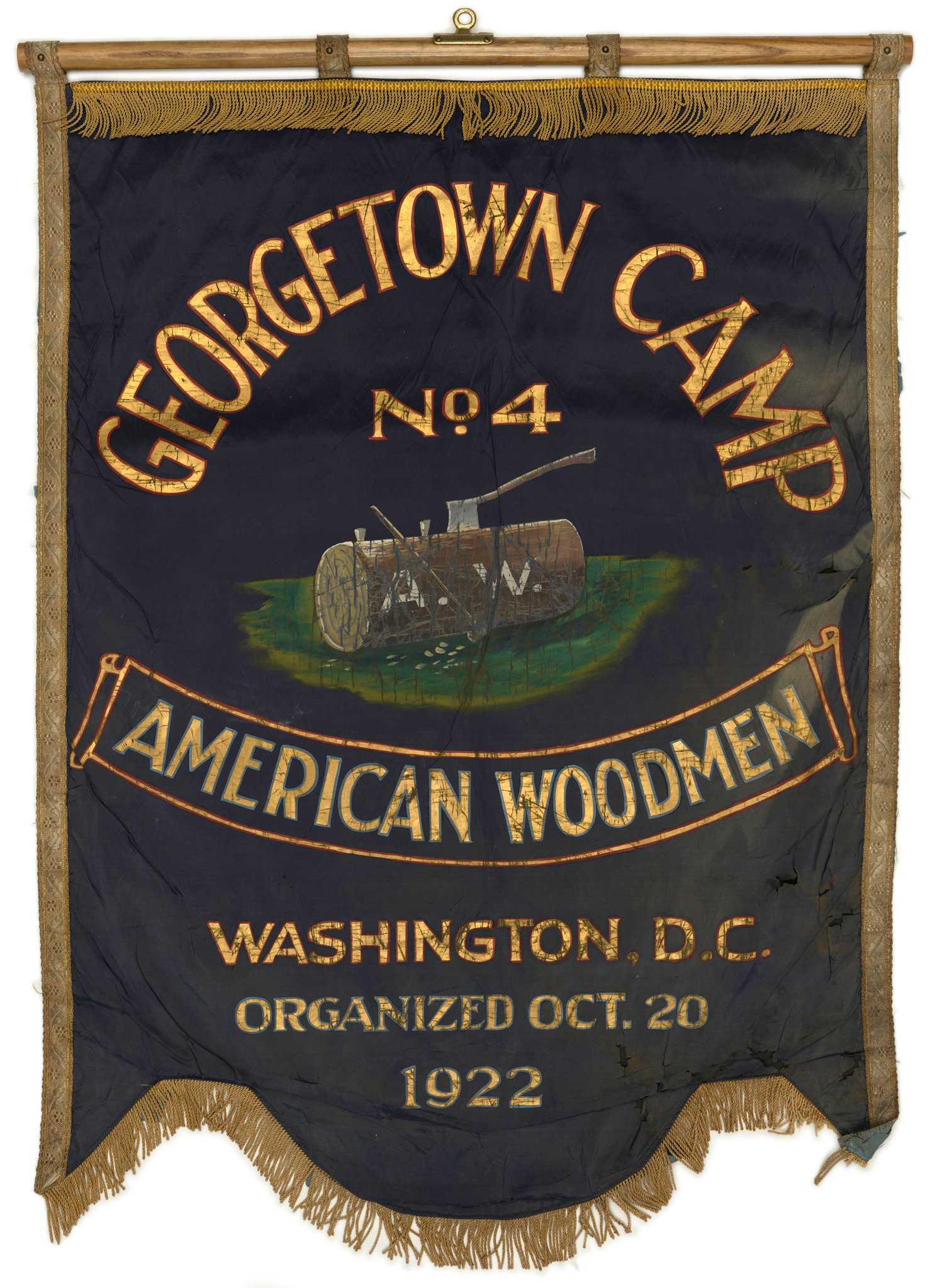 The banner dark purple with gold colored lettering with an image of an ax stuck in a log on green grass is at the center.