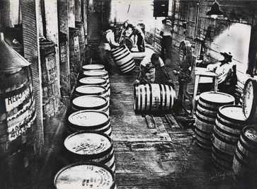 Man rolling whiskey barrels through a production floor