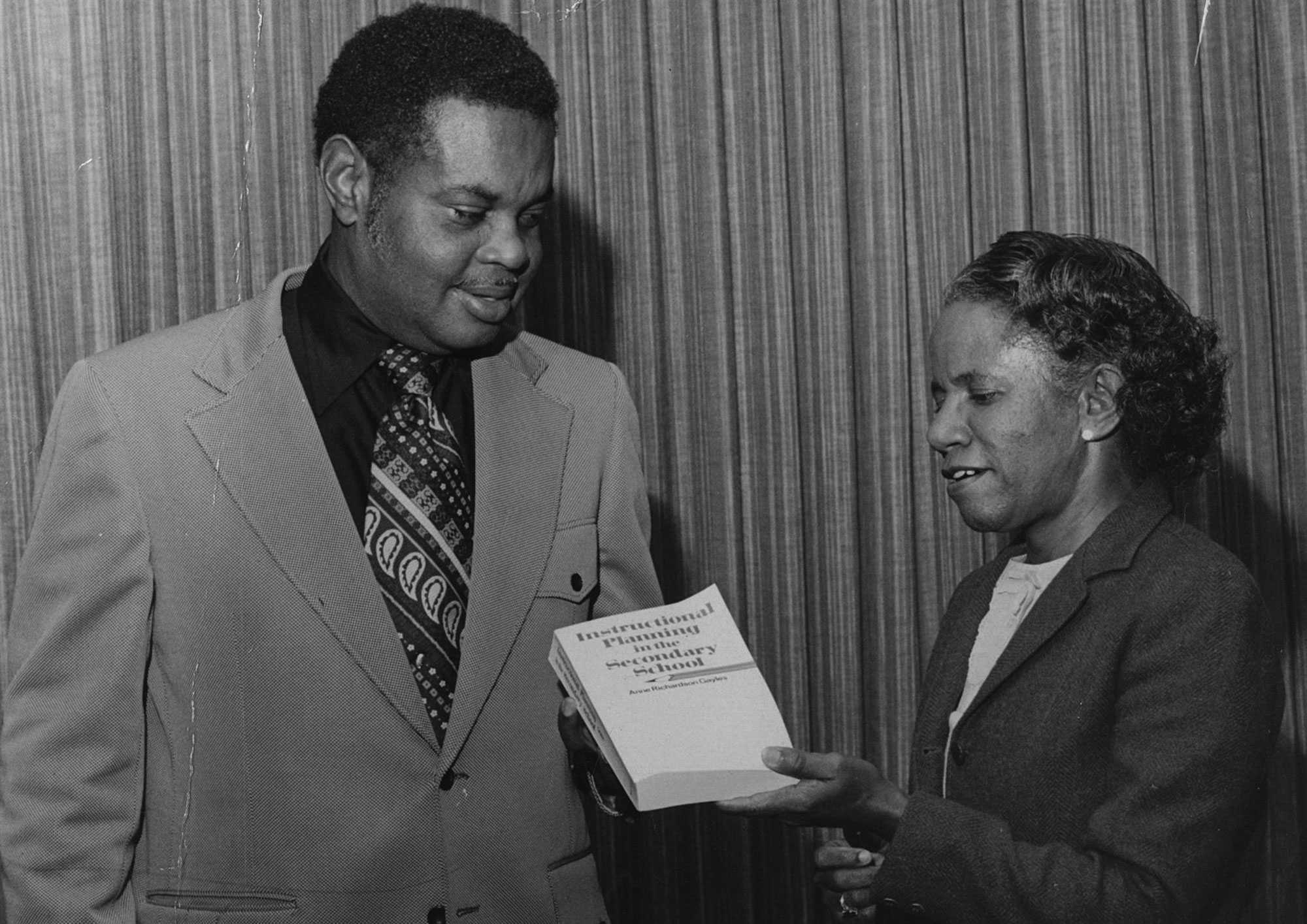 Photo of a man and woman looking at a book titled "Instructional Planning in the Secondary School."