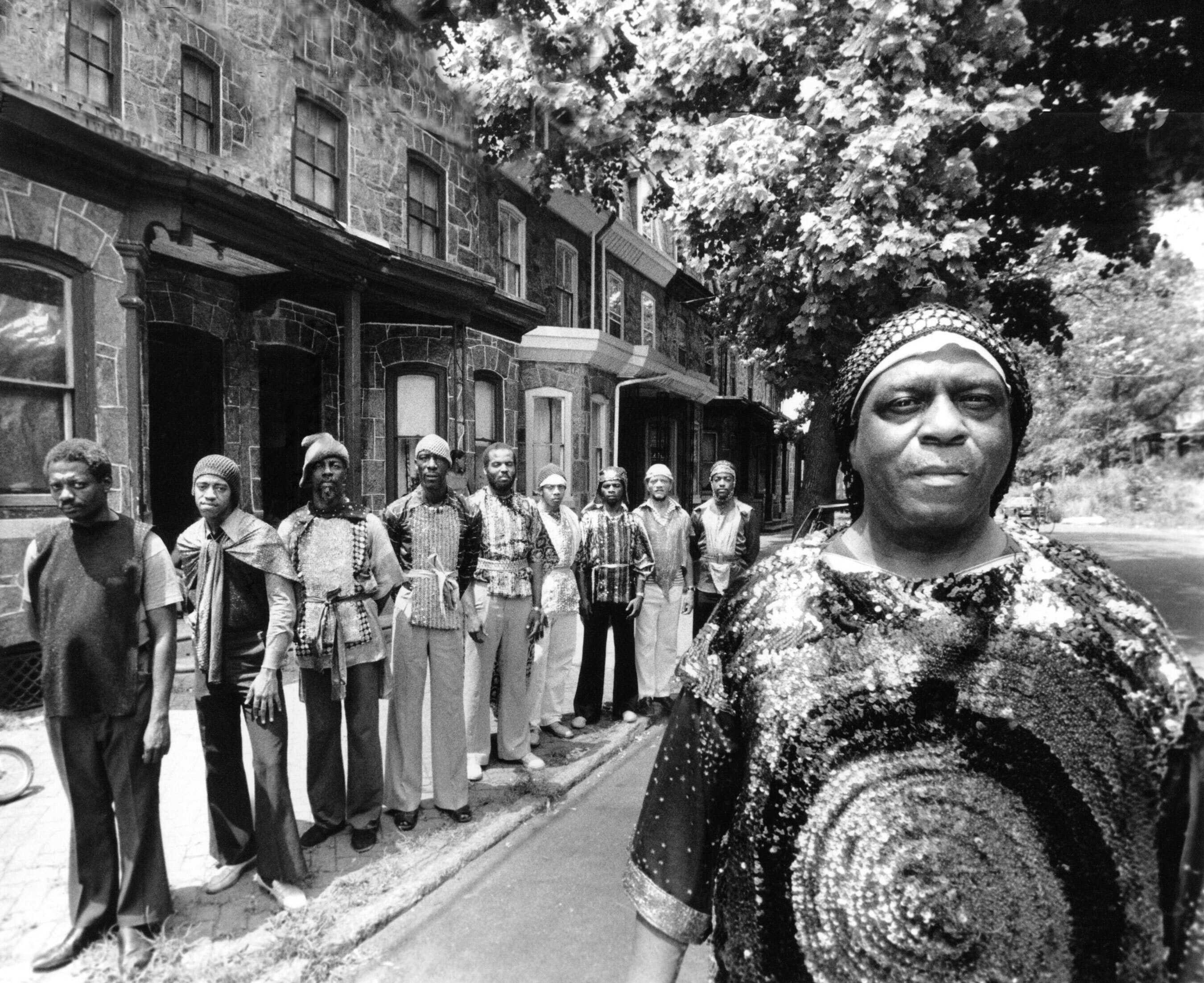 Sun Ra poses in front of his row house in the Philadelphia suburb with some of his Arkestra members.