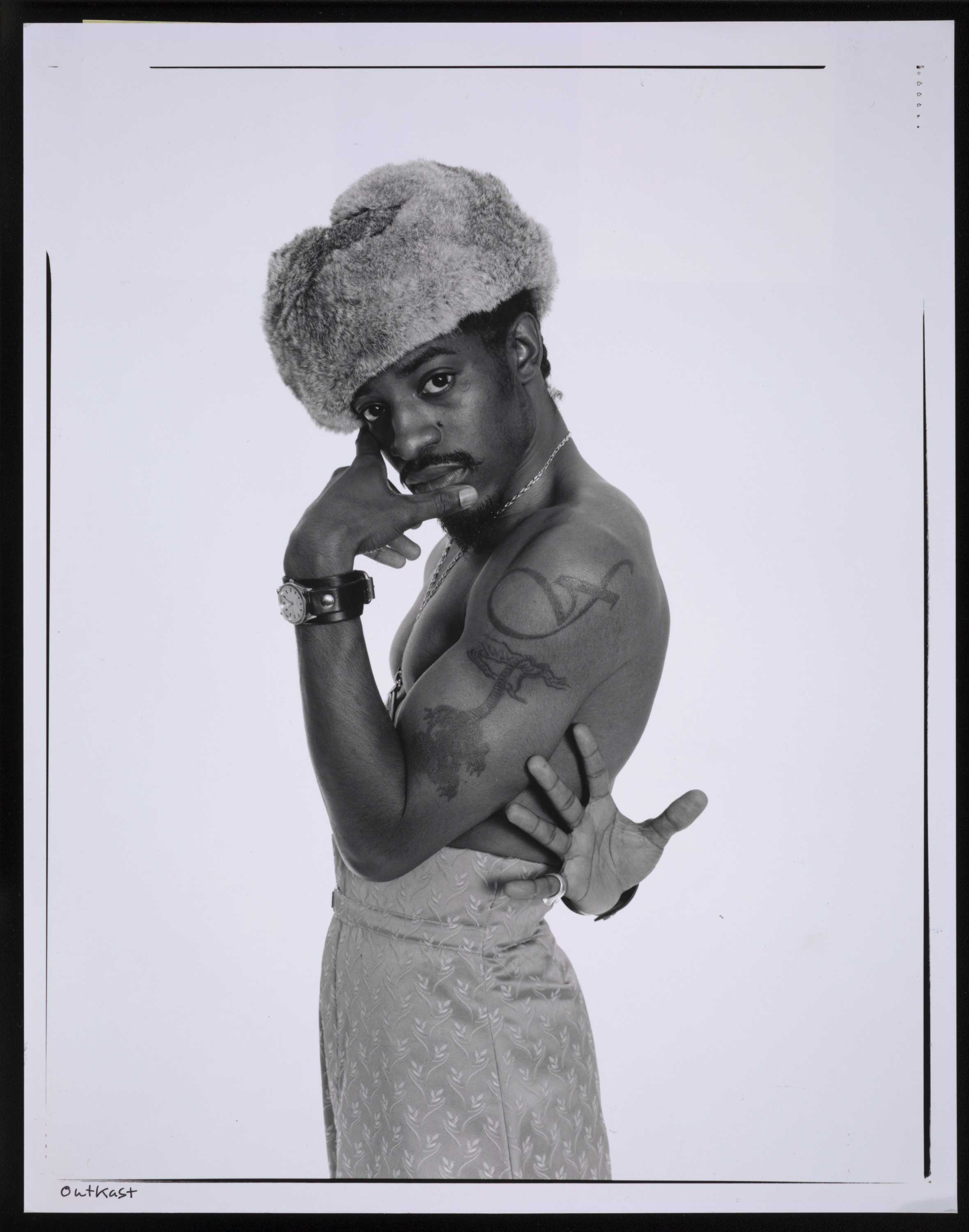 Black and white photograph of Andre 300 posing in a fur hat and looking directly at the camera.