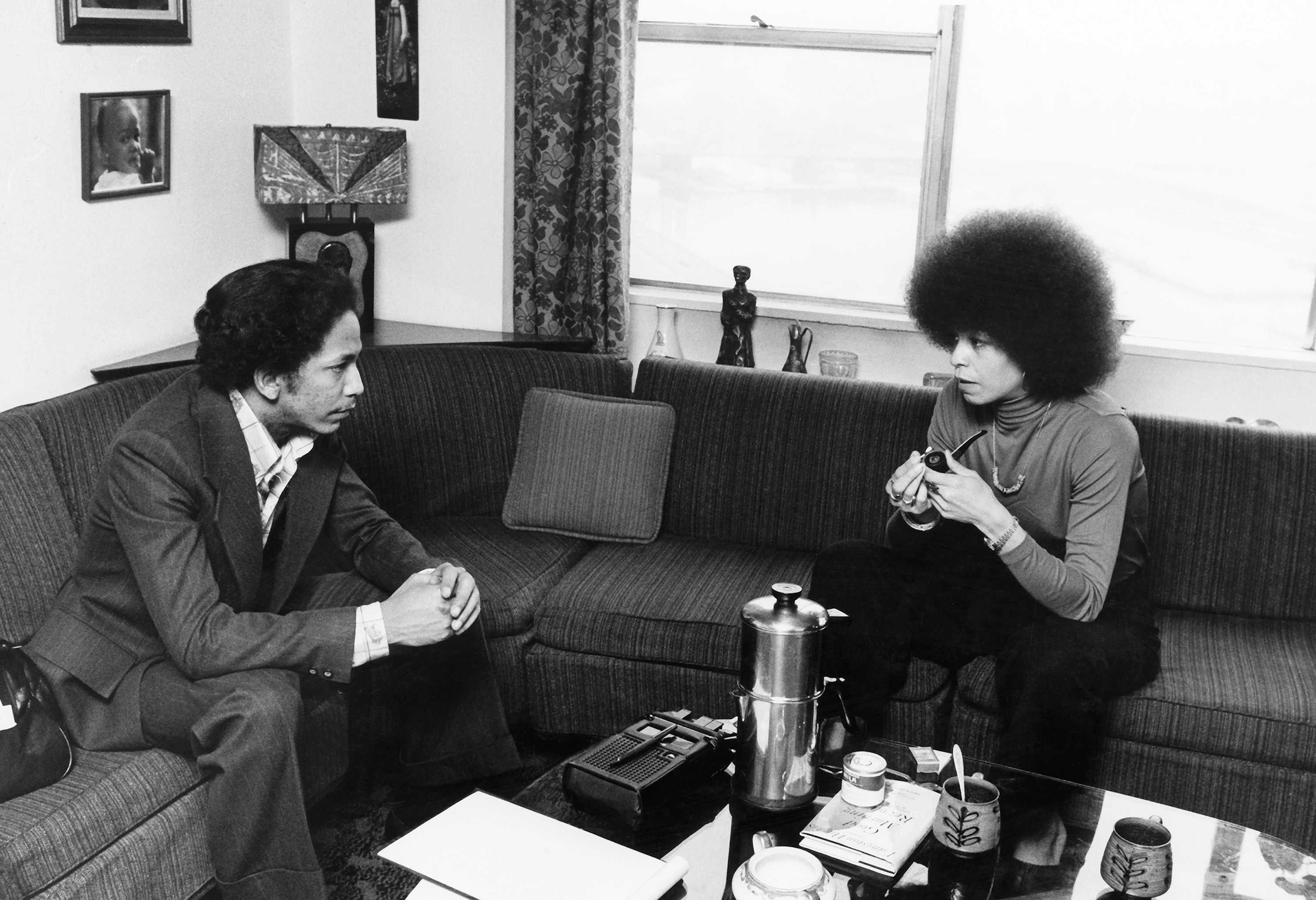 Black and white photograph of Robert A. DeLeon interviewing Angela Davis seated on sofas