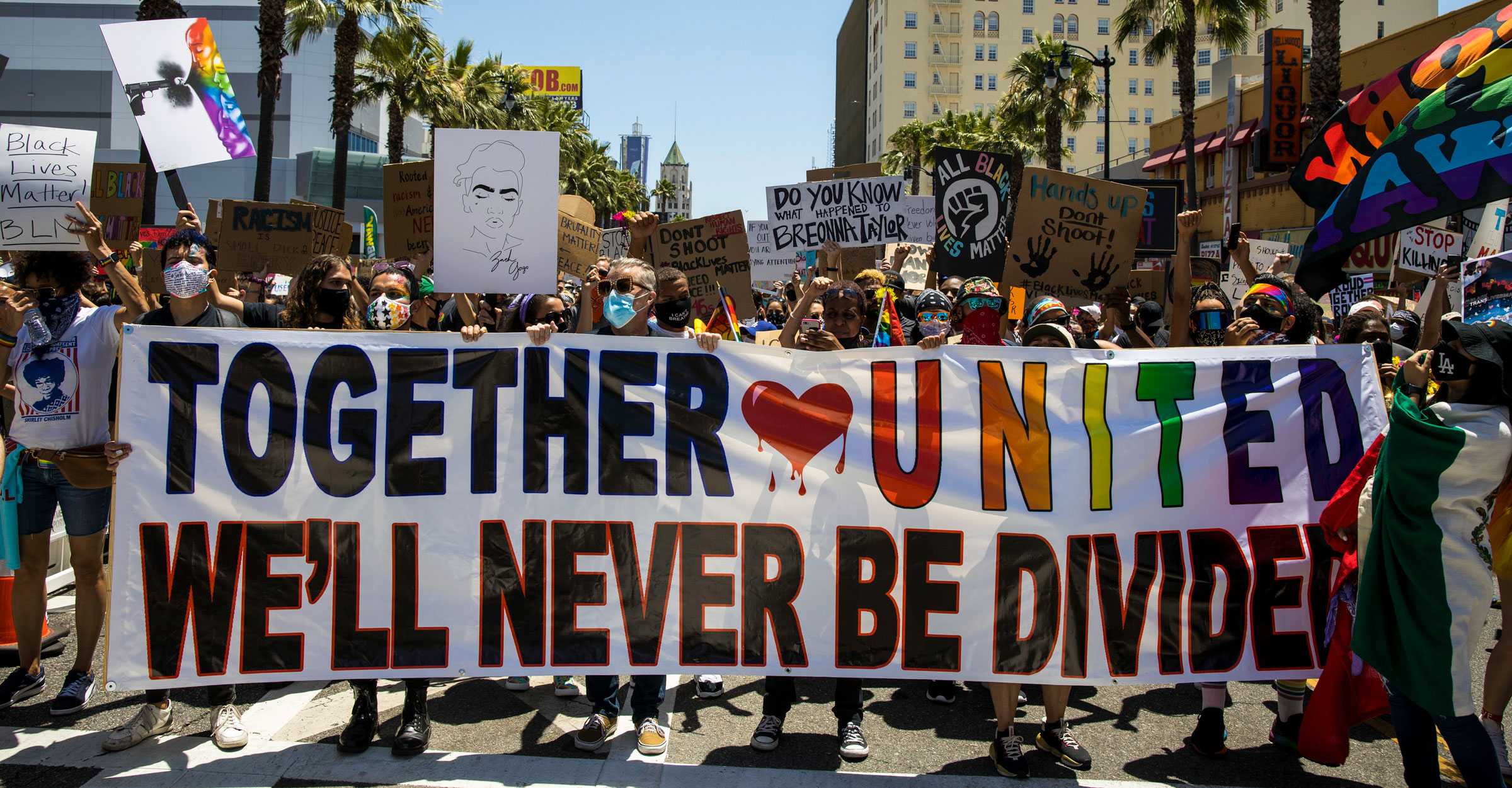 Protestors walk in the streets with a large banner that says Together United; We'll Never be Divided"