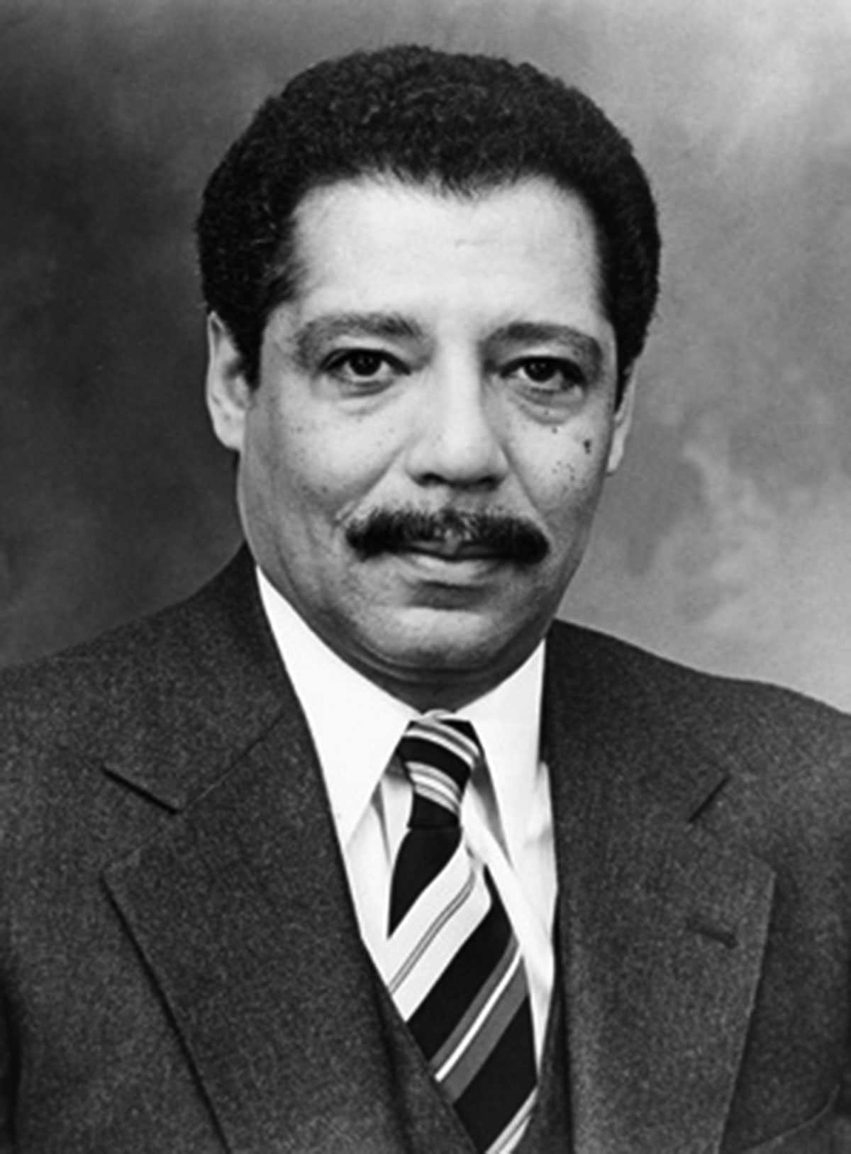 Black-and-white photo of a man in a suit and tie against a plain backdrop.