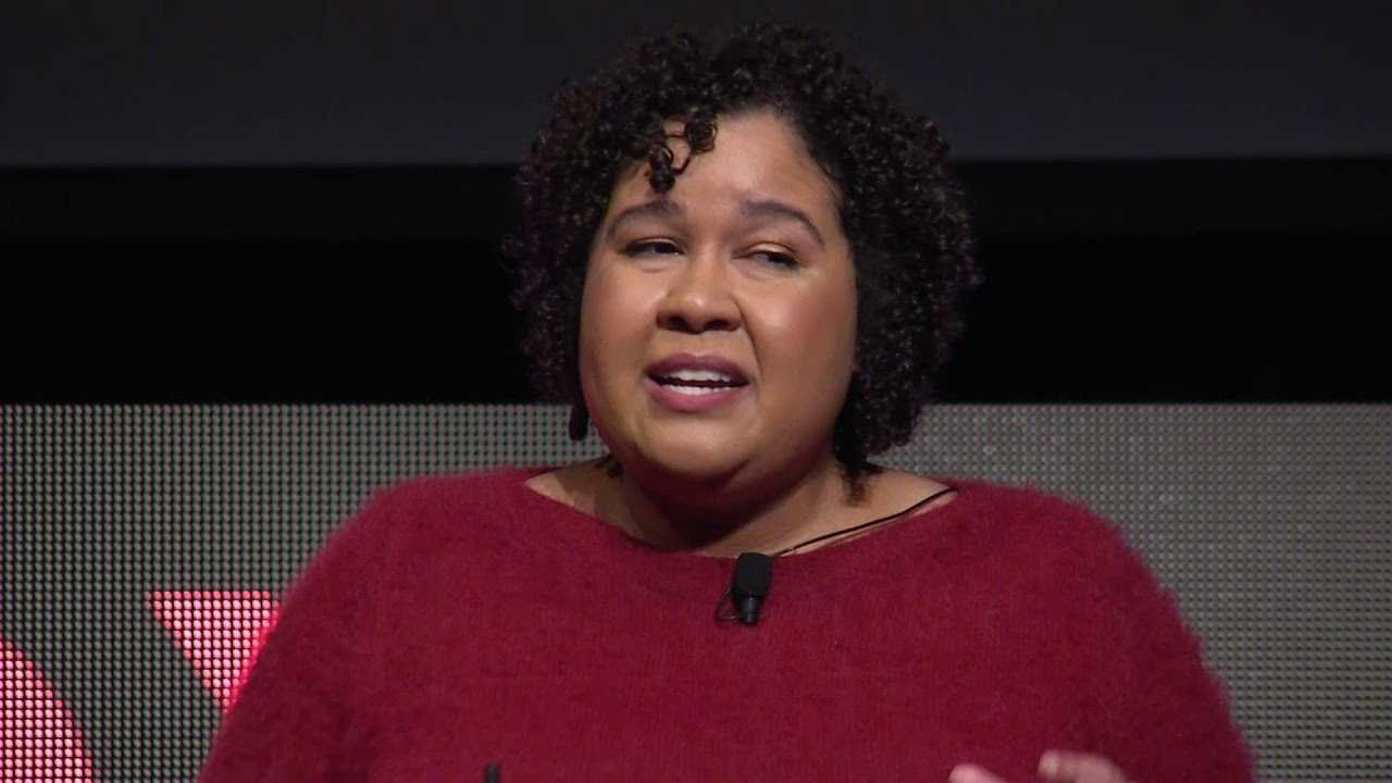 A still image from Jobie Hill's TedX presentation. Hill is speaking on stage.