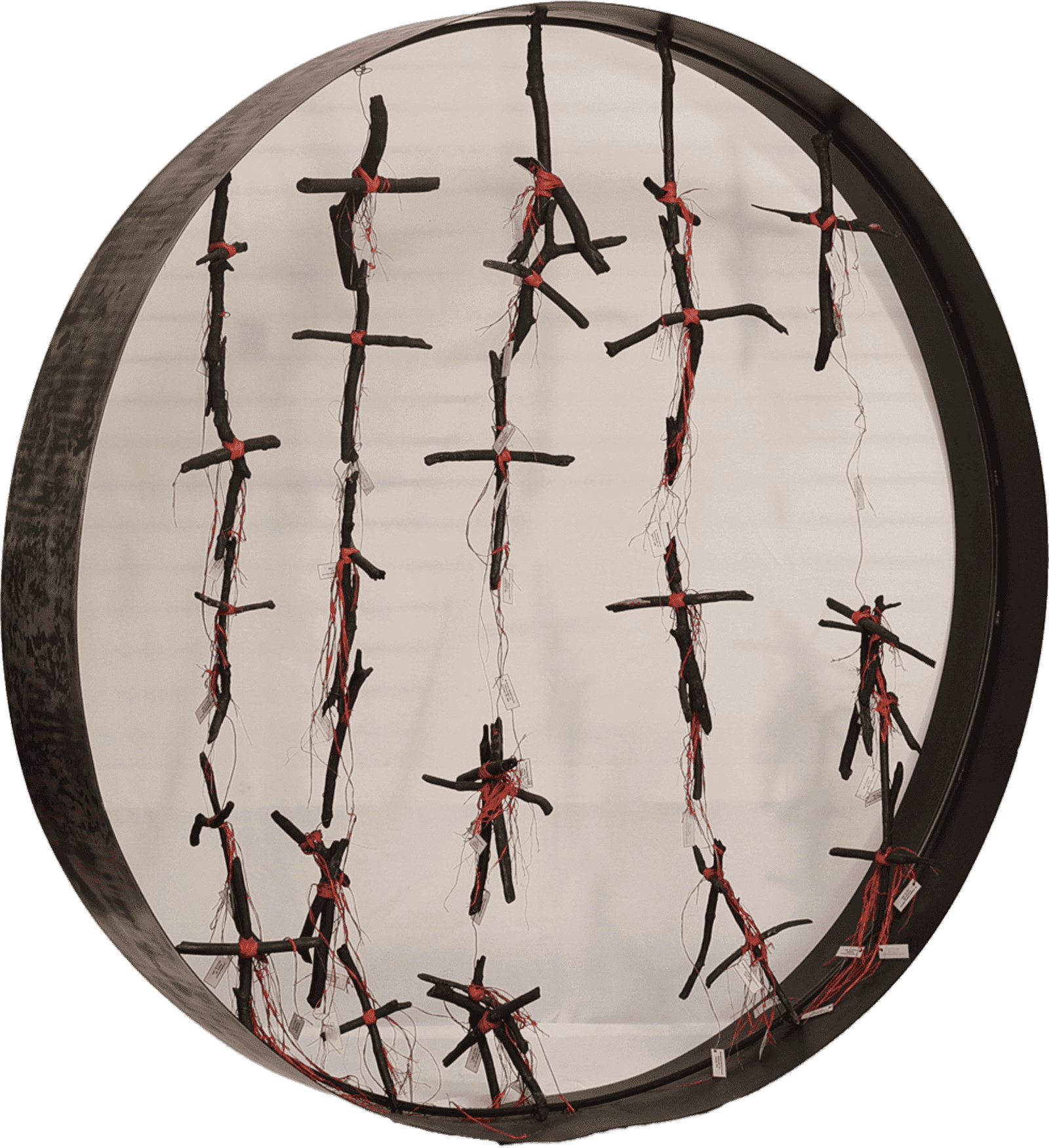 Circular frame with vertical rows of black sticks tied with red string and loose threads hanging inside.