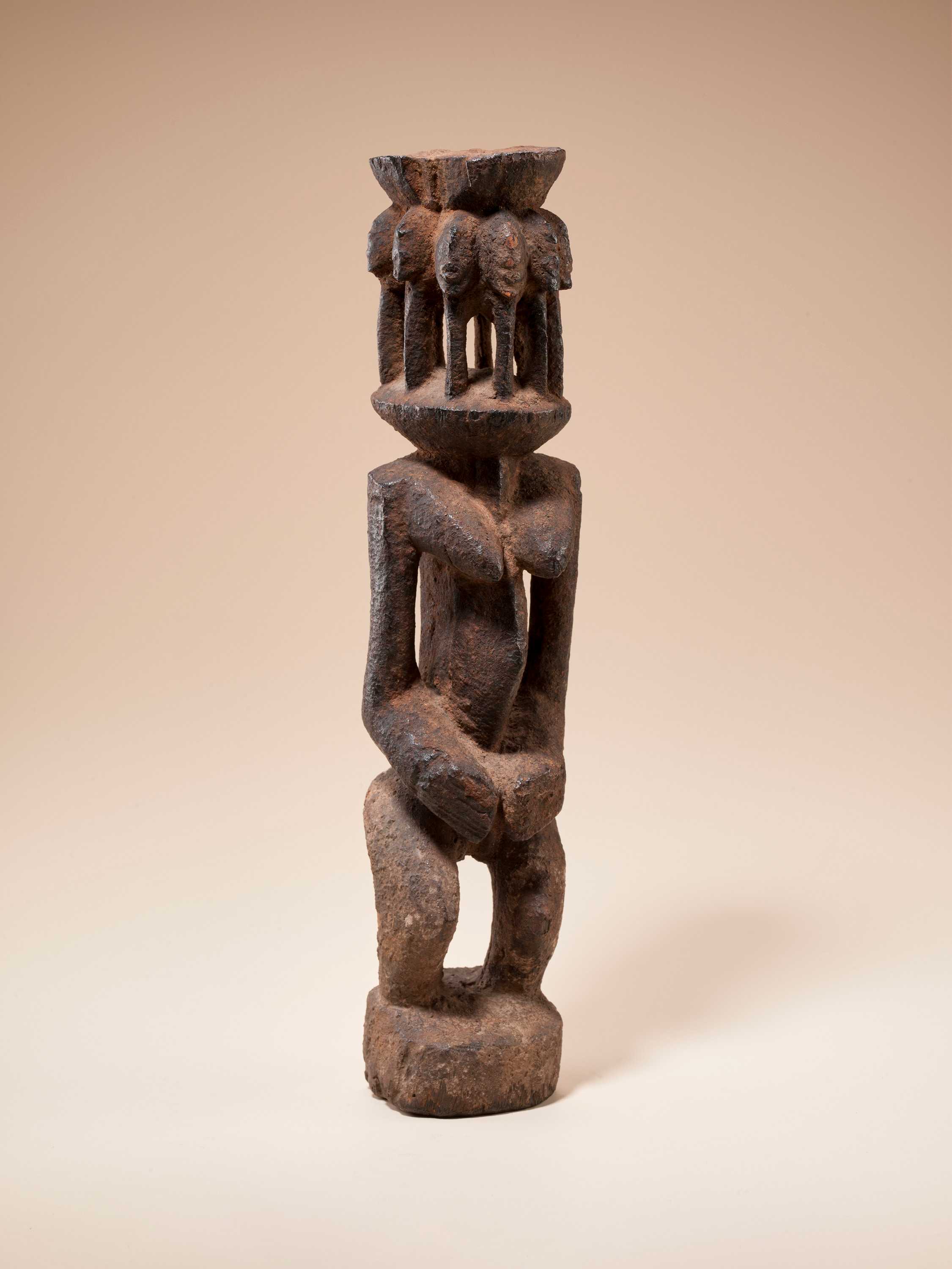 Small brown statue of a female figure with multiple heads
