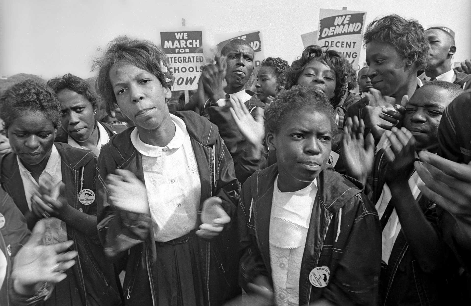 A digital image of The March on Washington for Jobs and Freedom, which took place in Washington, DC on August 28, 1963. The image depicts a close-up of a crowd of young women dressed in school-like uniforms clapping their hands.