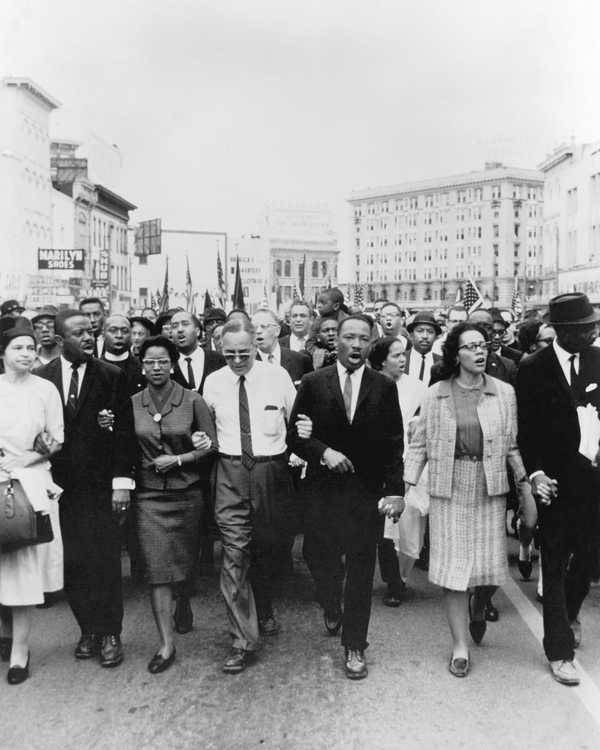 Black and white photograph of Dr. Martin Luther King Jr. and Coretta Scott King lead a group of protesters during the Selma to Montgomery March
