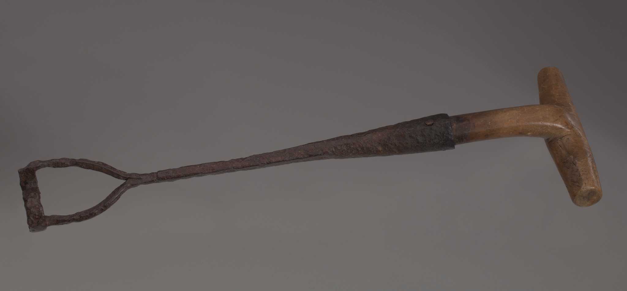 Slave branding iron with "S" head. Branding iron has a "T" shaped wood handle, attached to brand using a nail. Iron brand is cylindrical and breaks in to two prongs that attach to the top and bottom of the "S" head.