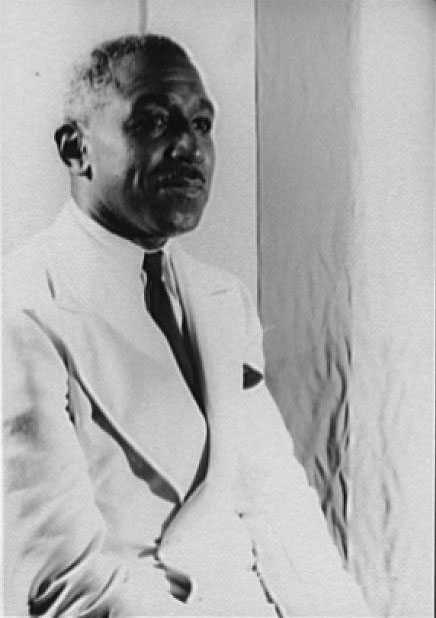 A black and white photograph of George Schuyler in white suit and dark tie.