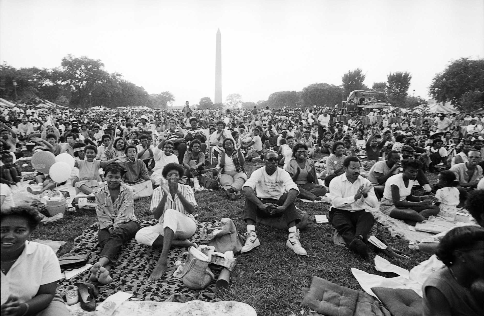 Photograph of picnic goers seated in front of the Washington Monument