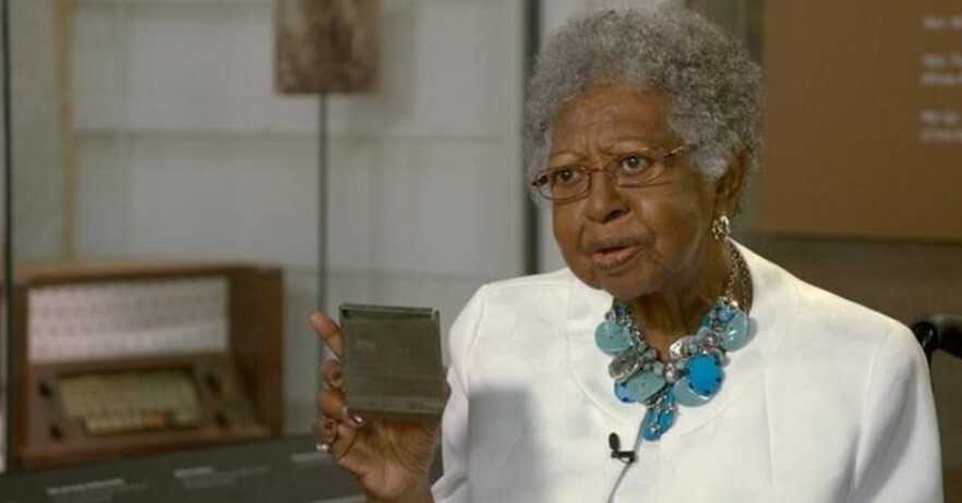 Image of Elaine Thompson holding her ancestor’s tin wallet and freedom paper