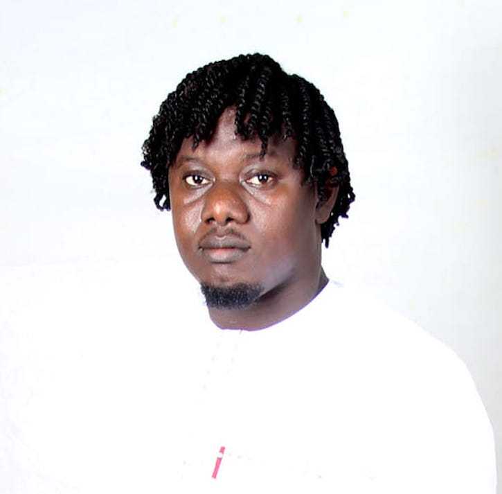 A headshot of Oghenechovwe Donald Ekpeki. He is wearing a white t-shirt against a white background.