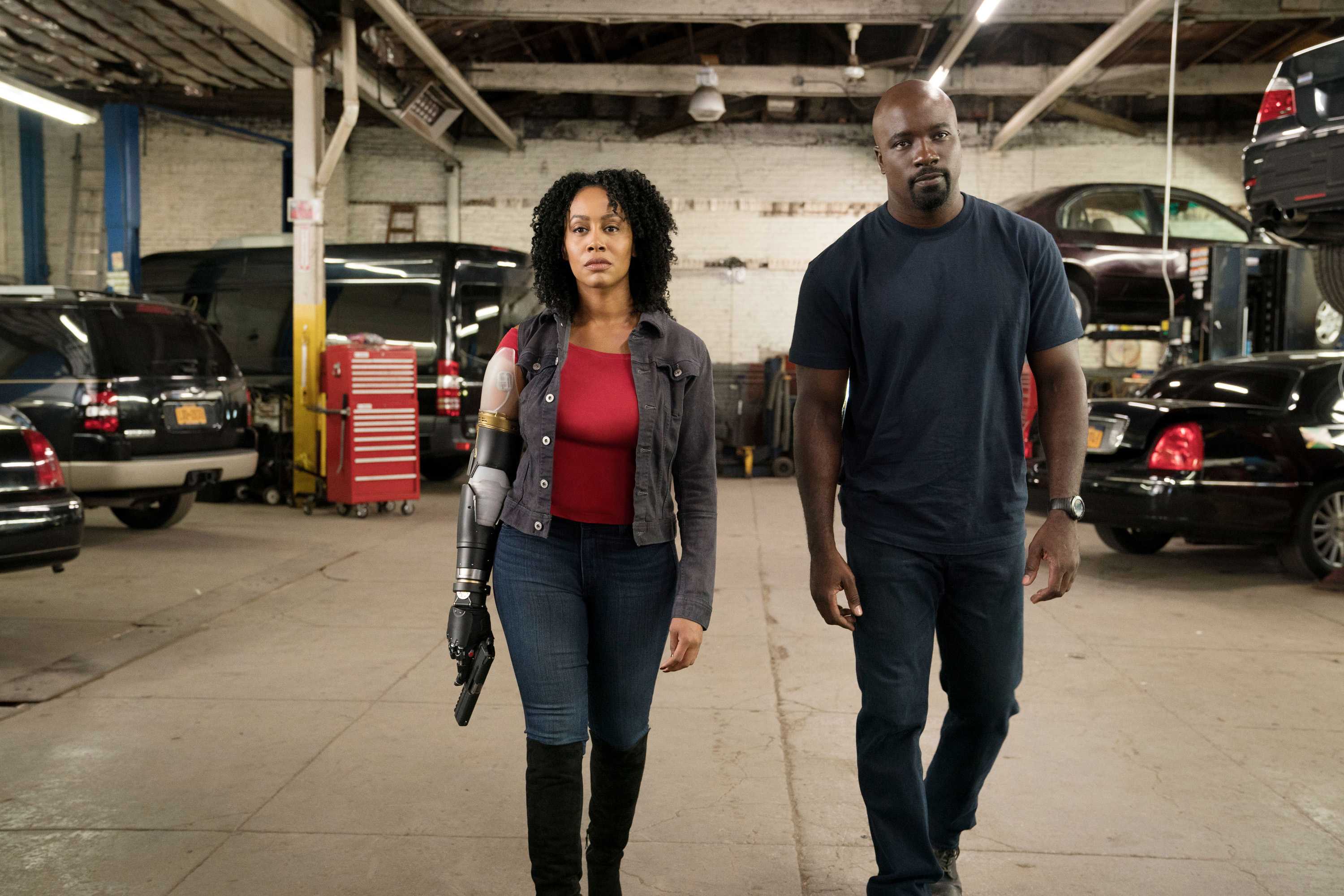 Simone Missick, playing as Misty Knight, and Mike Colter, playing Luke Cage, walking in an autoworkshop.
