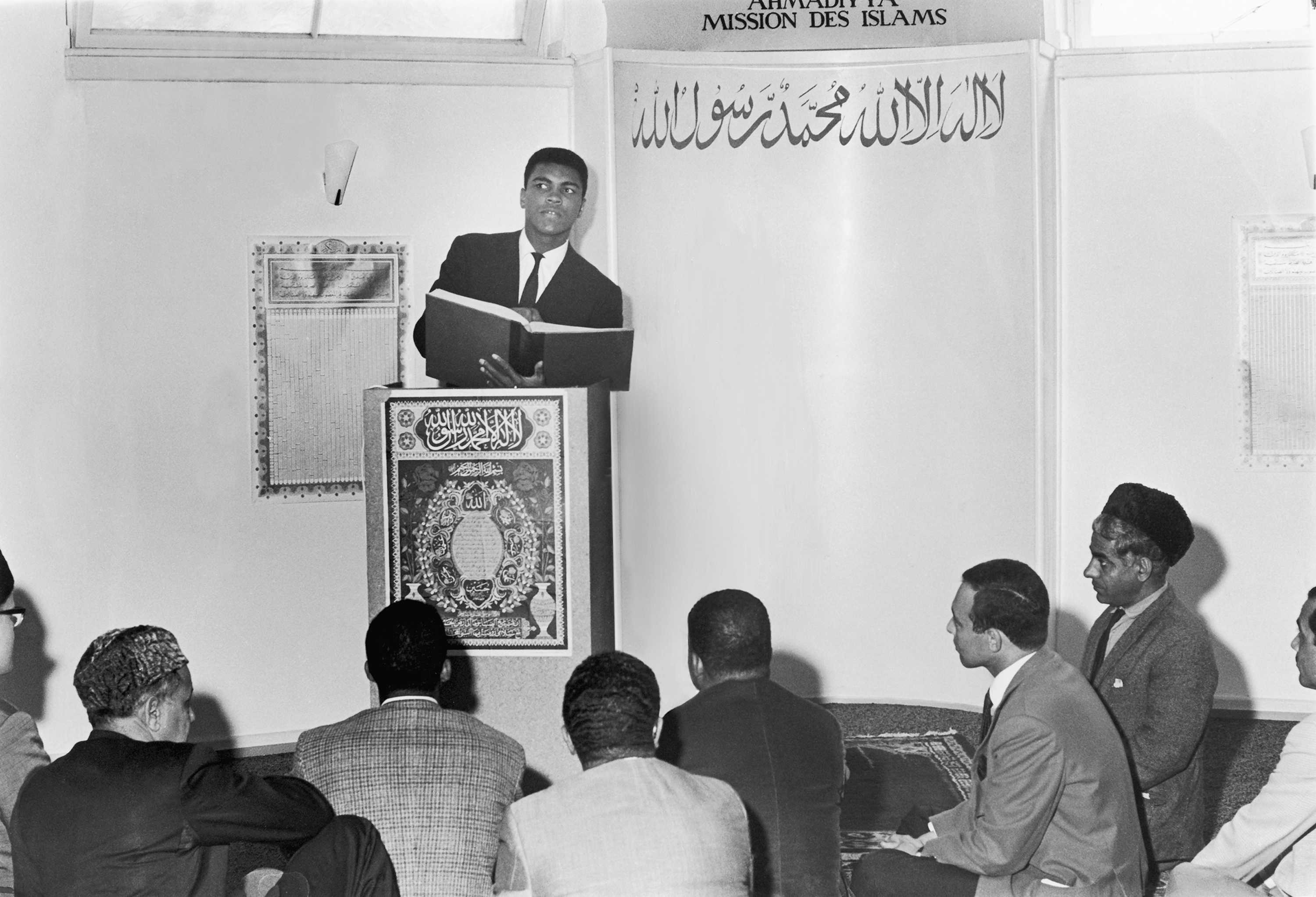 Black and white photograph of Muhammad Ali reading the Koran at a mosque