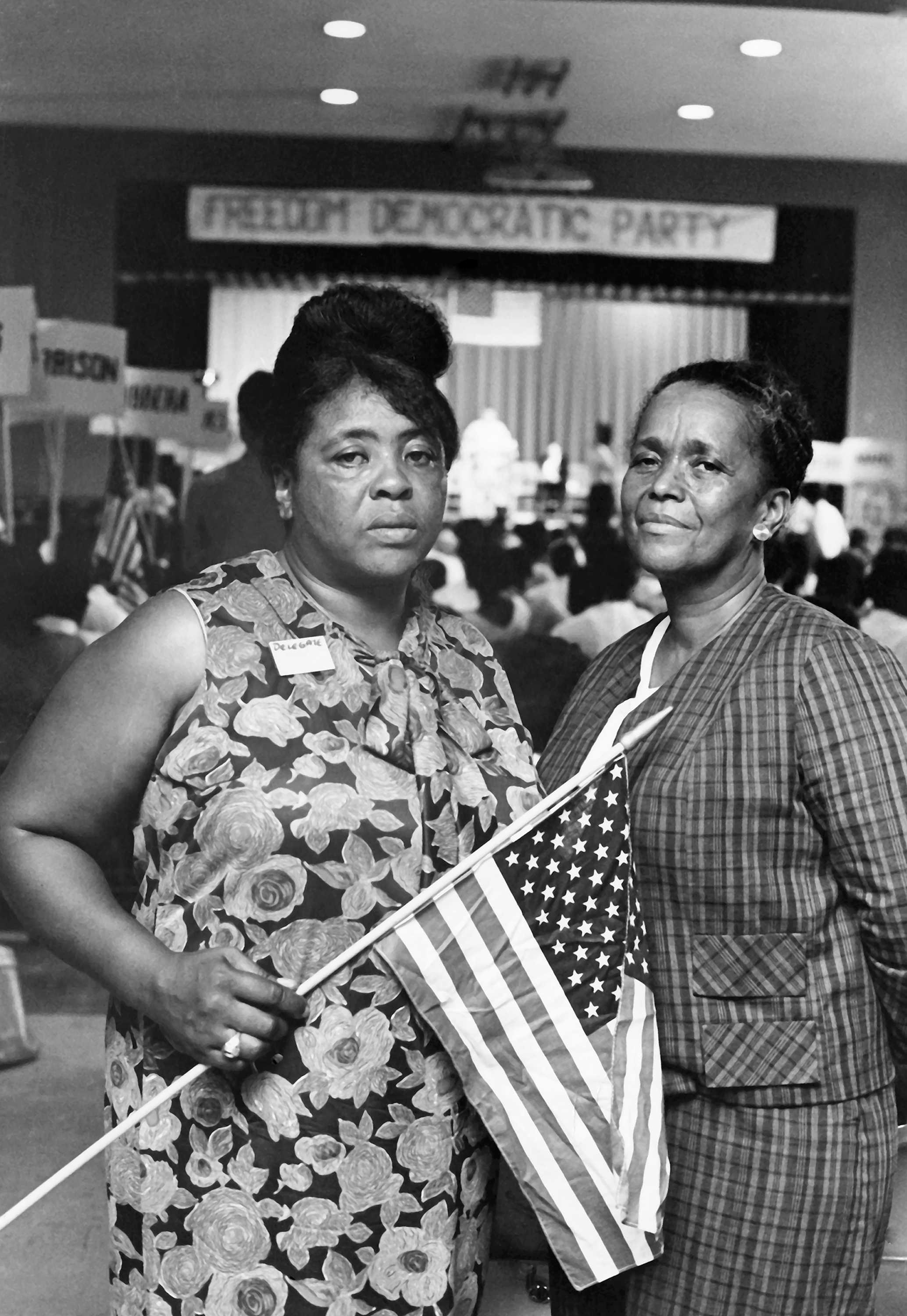 Black and white photograph of Fannie Lou Hamer and Ella Baker at the Mississippi Freedom Democratic Party state convention holding an American flag