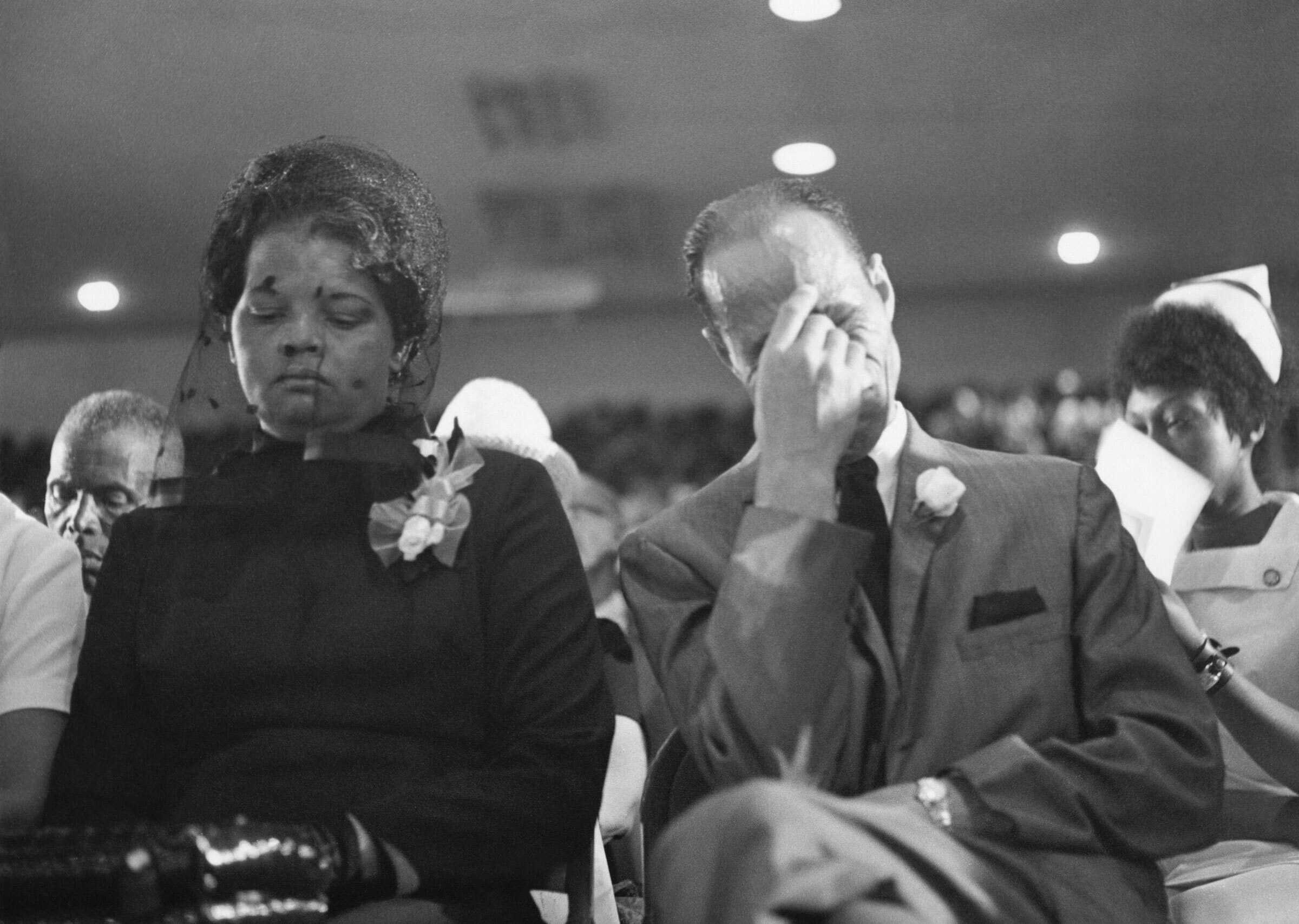A black and white photo of two people attending a funeral.