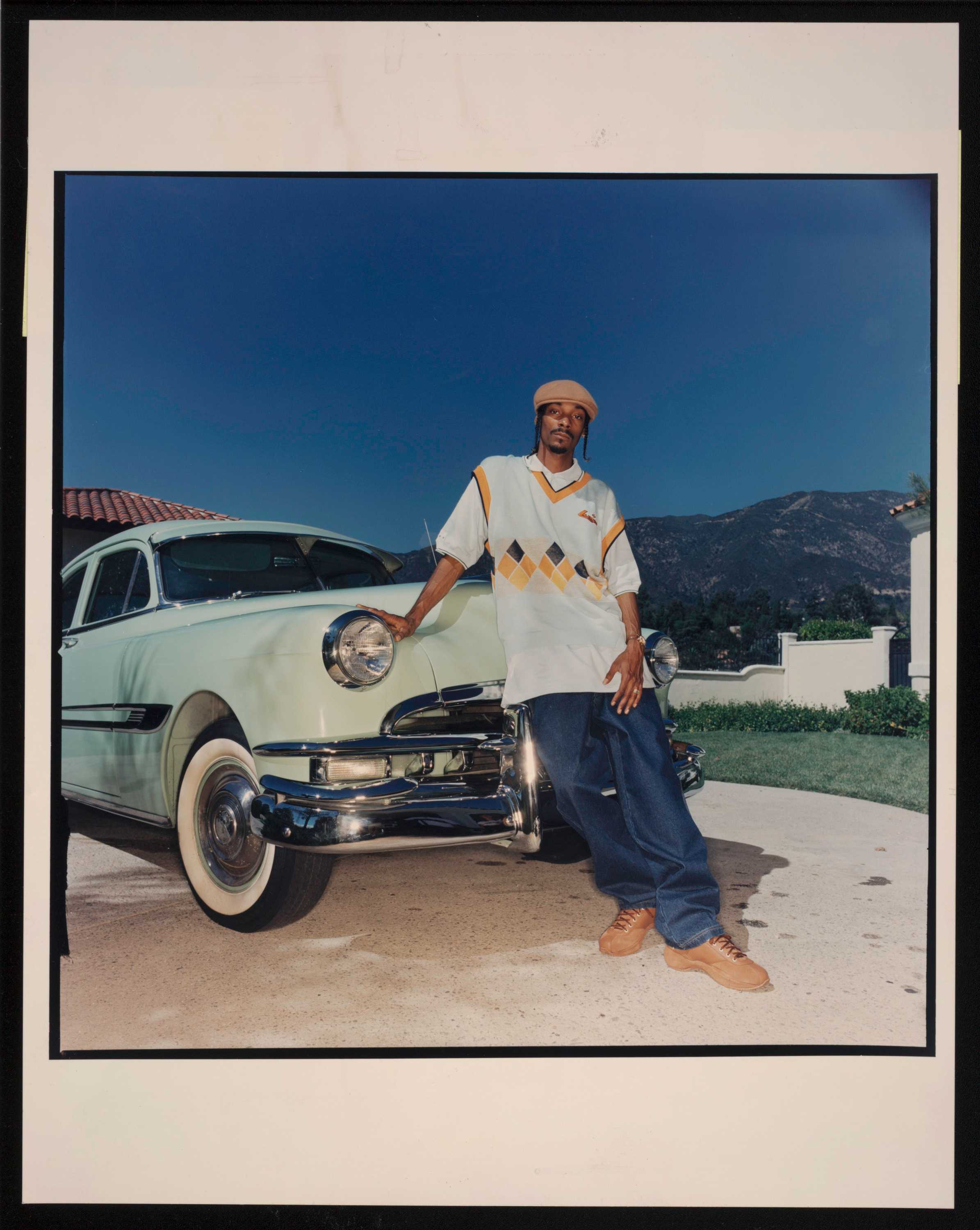 Man wearing vest and jeans standing in front of vintage car