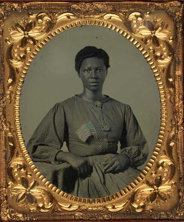 An ambrotype of an African American woman with a flag pinned to her chest inside an ordinate gold frame.